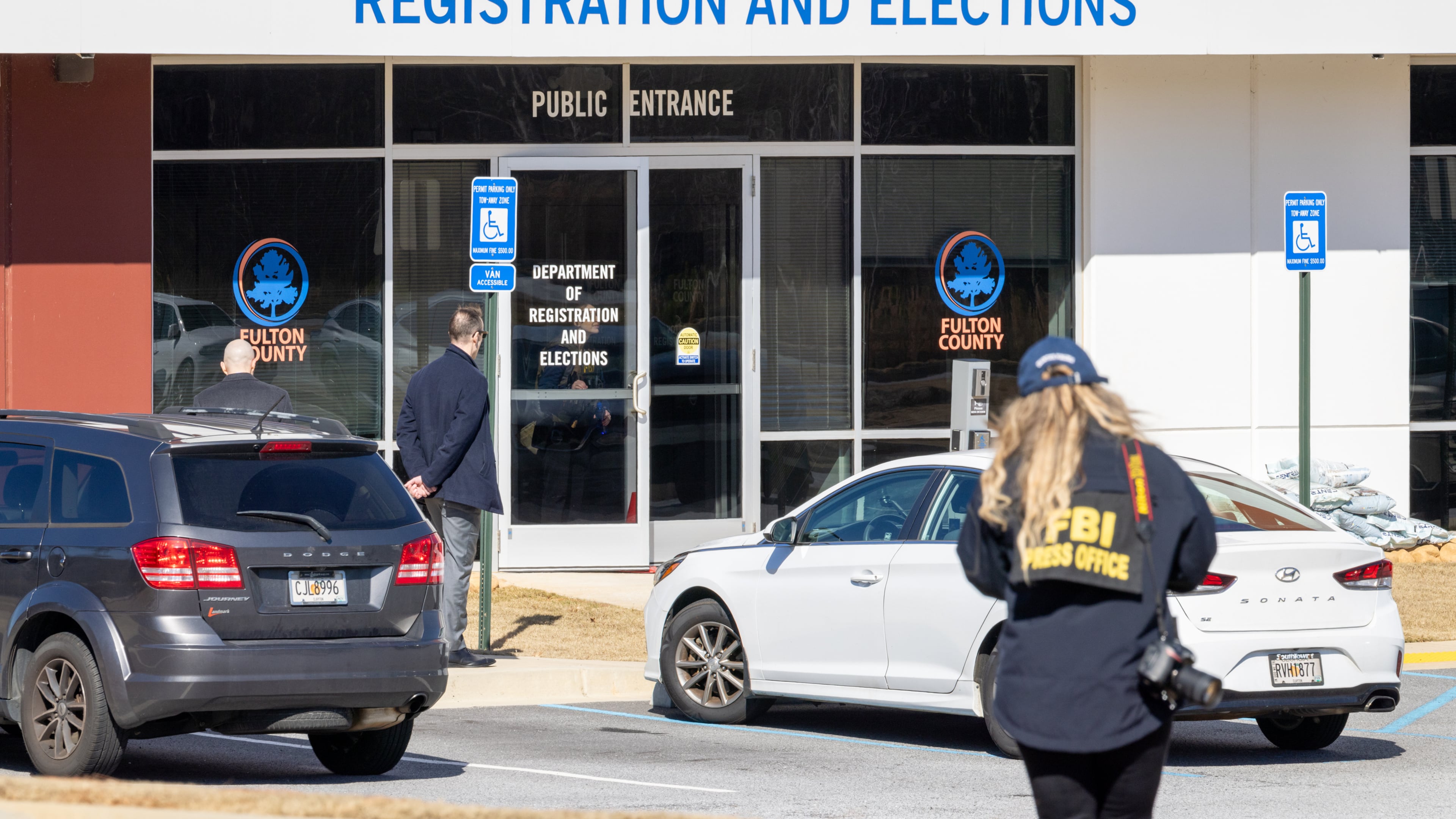 An FBI press office person approaches the Fulton County Election Hub and Operation Center, Wednesday, Jan. 28, 2026, in Union City, Ga. (Arvin Temka/Atlanta Journal-Constitution via AP)