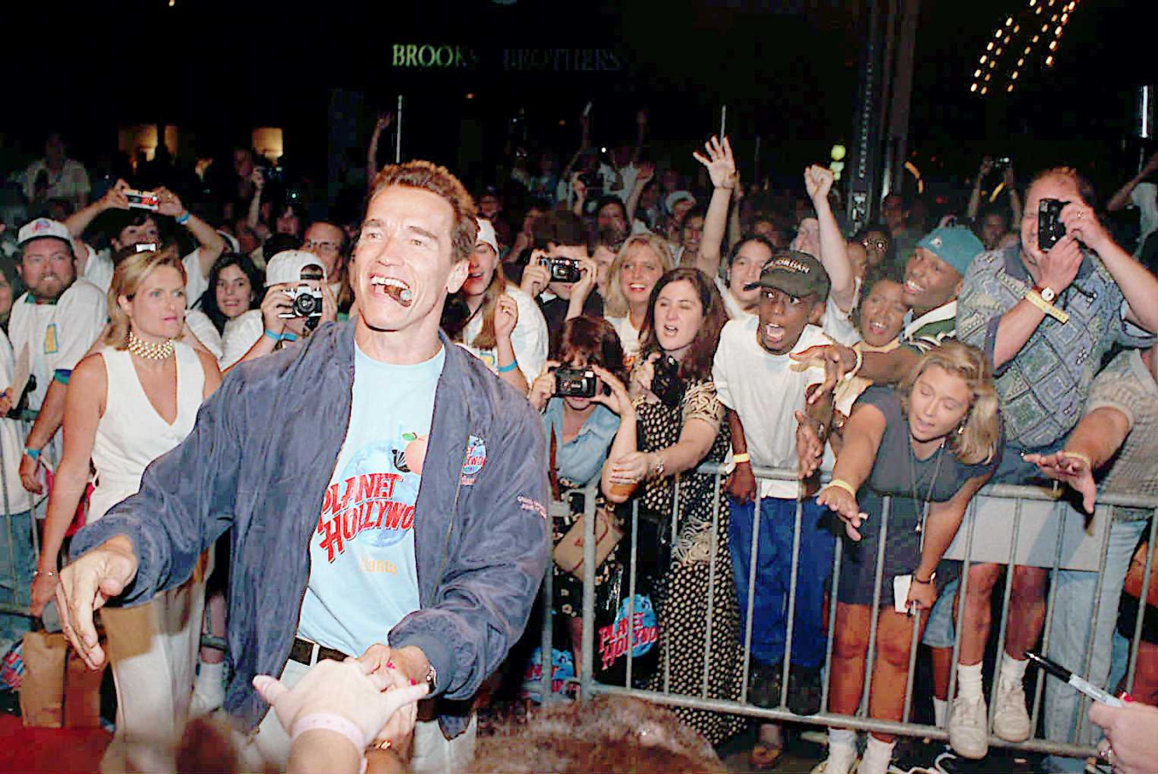 Arnold Schwarzenegger greets excited fans before heading into the grand opening of Planet Hollywood in Atlanta in June 1995.