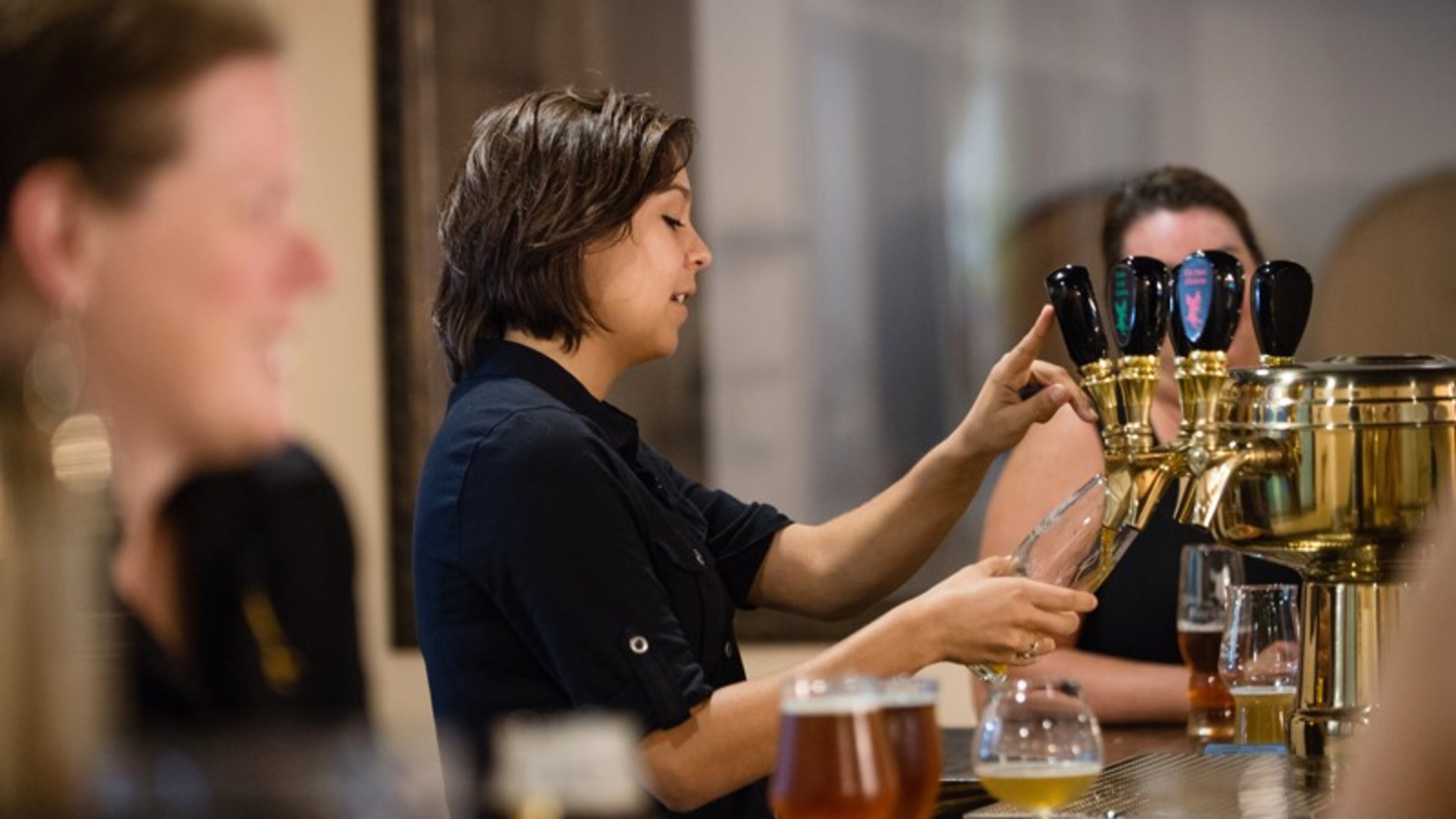 Olivia Morales, head of marketing, pours a beer for a visitor to the Abbey of the Holy Goats brewery in Roswell. Photo by Bita Honarvar/Special