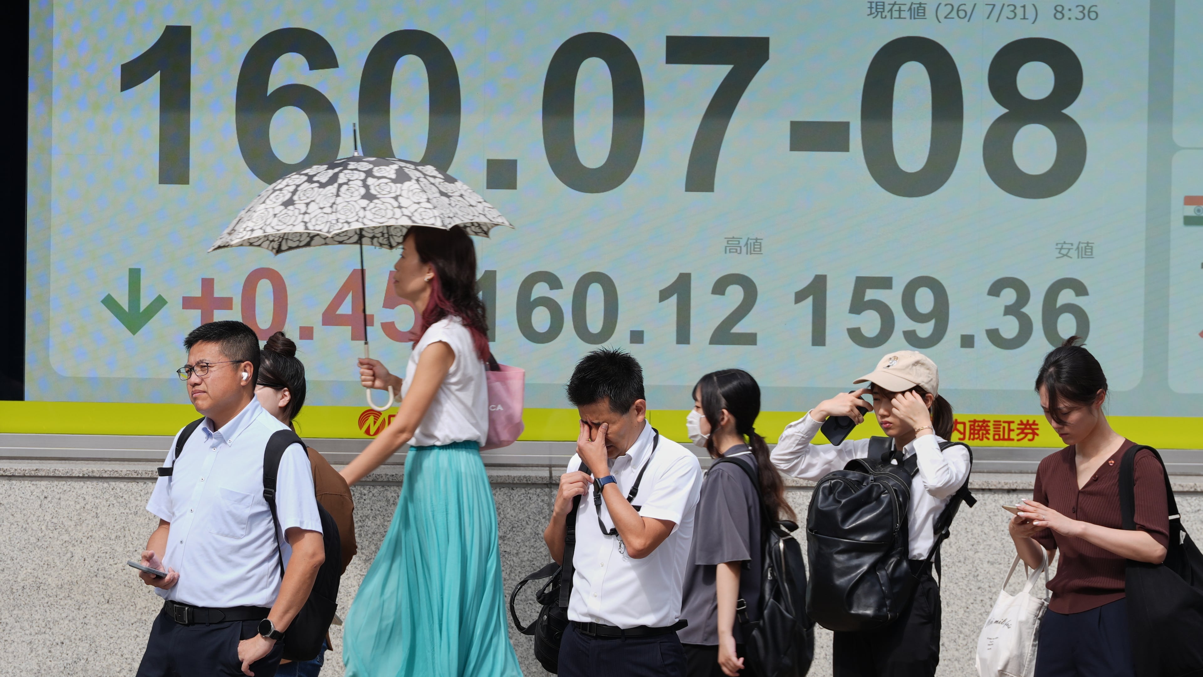 People stand in front of the electronic board showing Japanese Yen and U.S. Dollar exchange rate at a securities firm Friday, July 31, 2026. (AP Photo/Eugene Hoshiko)