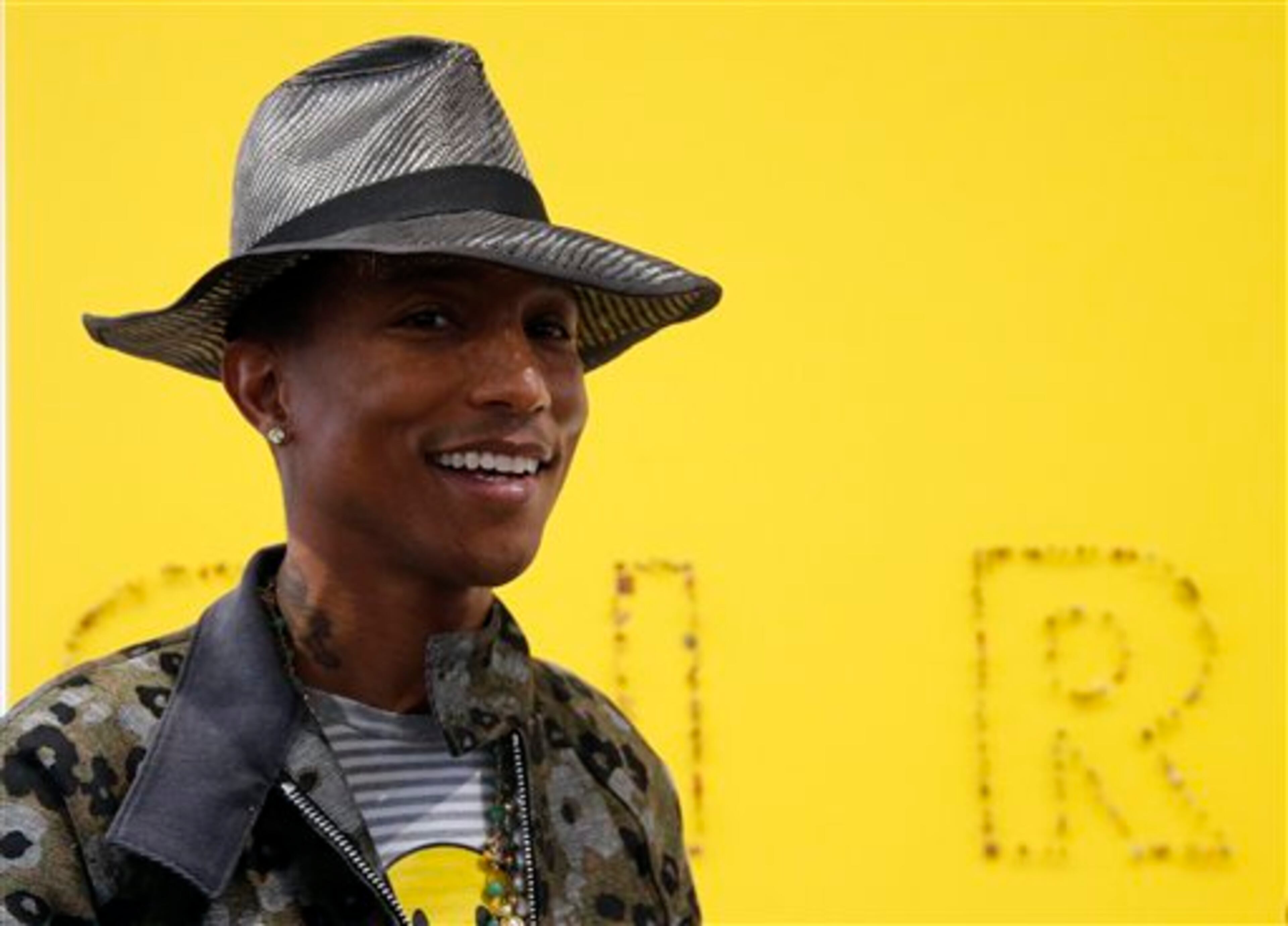 US singer Pharrell Williams poses during a press conference for the exhibition "GIRL" at the Perrotin Gallery in Paris, Monday, May 26, 2014. Williams curates an exhibition encompassing around 40 art pieces, presenting their visions of femininity, muses, female creativity and freedom. The show opens on May 27 and runs through June 27, 2014. The piece behind Williams is "GIRL" by French artist Guy Limone. (AP Photo/Francois Mori)