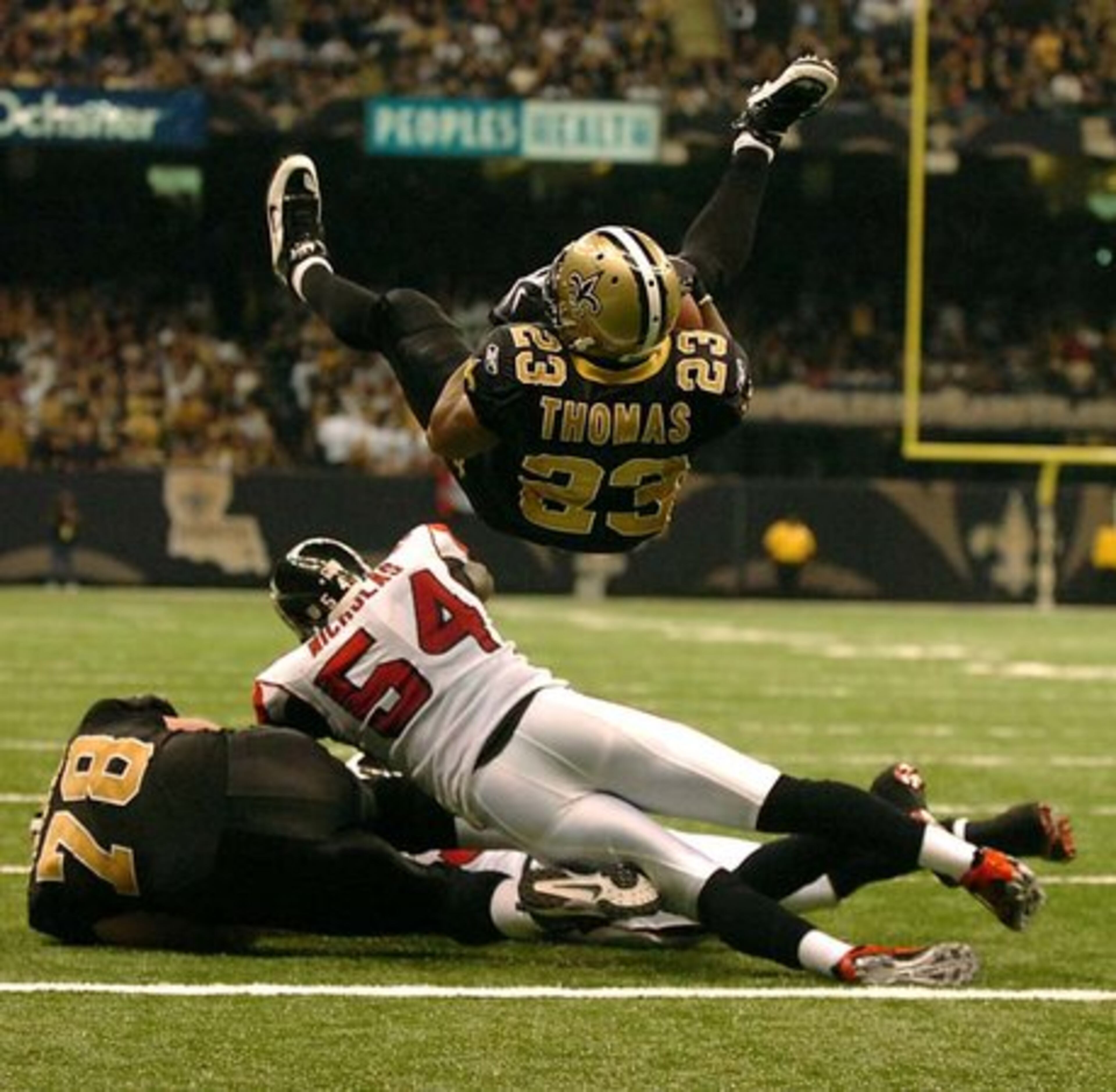 Saints running back Pierre Thomas dives into the end zone over Falcons linebacker Stephen Nicholas.