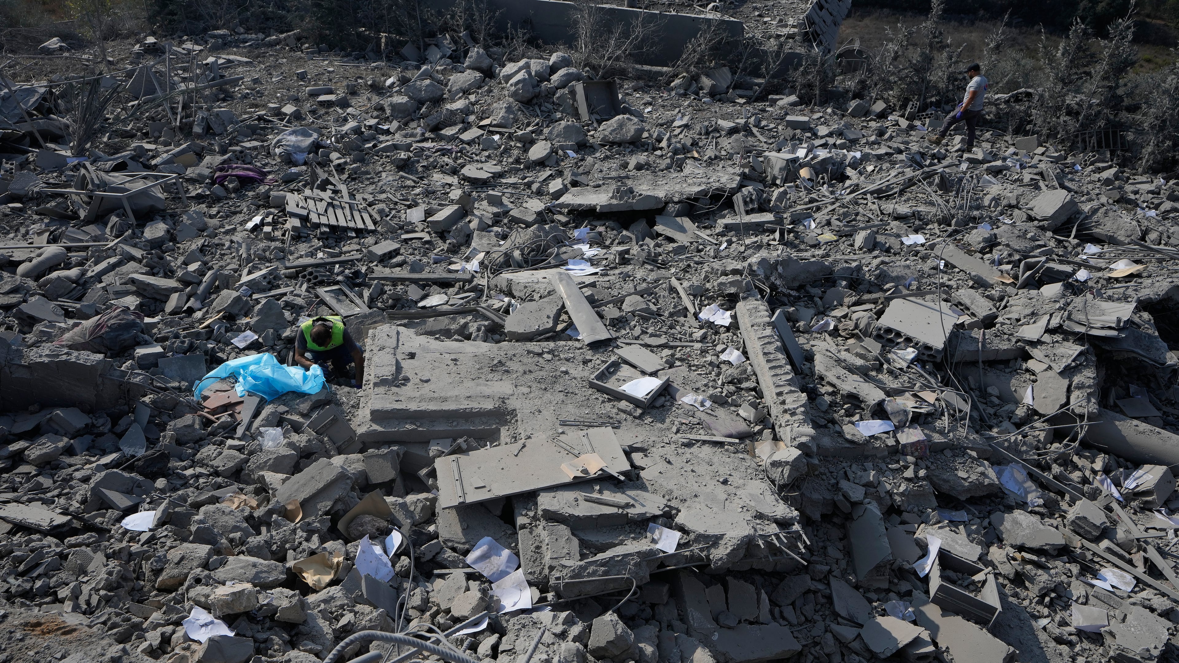 A rescue worker, left, searches for victims under the rubble of a home that was hit by an Israeli airstrike in Ansar village, southern Lebanon, Saturday, Aug. 15, 2026. (AP Photo/Mohammed Zaatari)