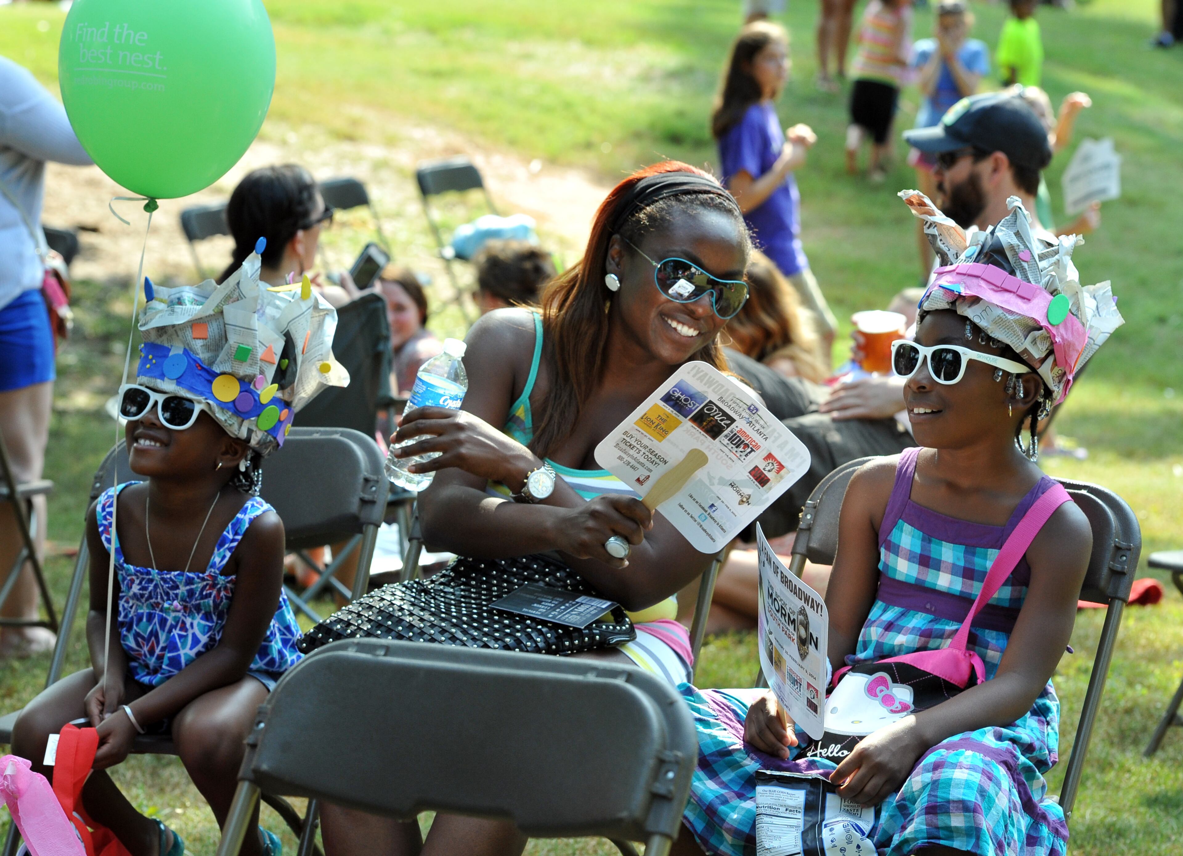 Gina Lemorin (center) and her daughters Ariana (left), 5, and Akina, 8, enjoy the live performance during Grant Park Summer Shade Festival on Saturday, August 24, 2013. The Grant Park Summer Shade Festival features an artist market, children's activities, great food, live music and the Adams Realtors 5K Run for the Park. The Children's Fun Center is a family favorite with storytellers, jugglers, sing-a-longs and kid-sized make-and-take projects. HYOSUB SHIN / HSHIN@AJC.COM