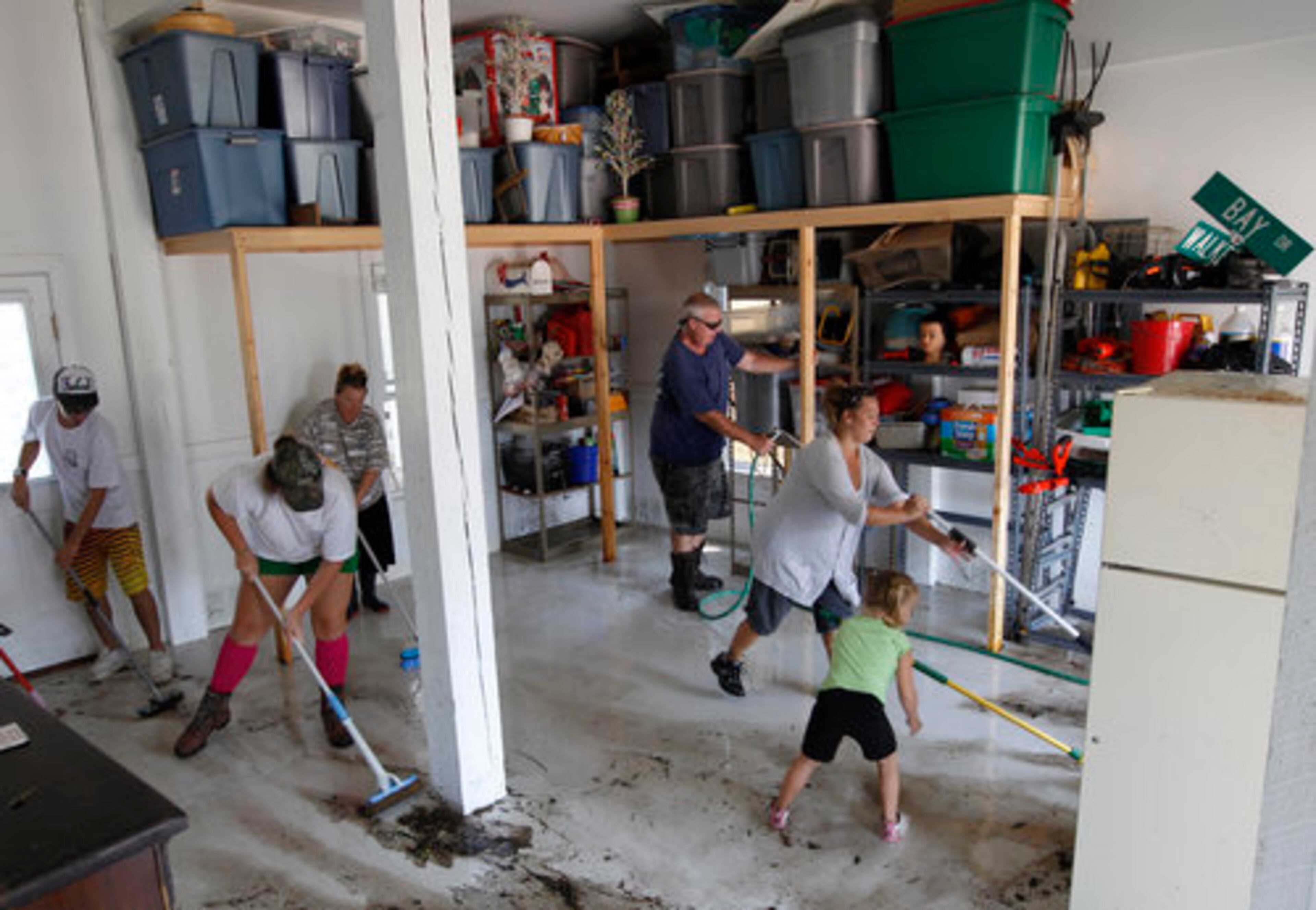 Marc James, rear center, and members of his family clean up the house of a friend who evacuated before Hurricane Irene, after it was flooded by a storm surge on the Outer Banks in Kill Devil Hills, N.C., Sunday, Aug. 28, 2011 in the aftermath of Hurricane Irene.