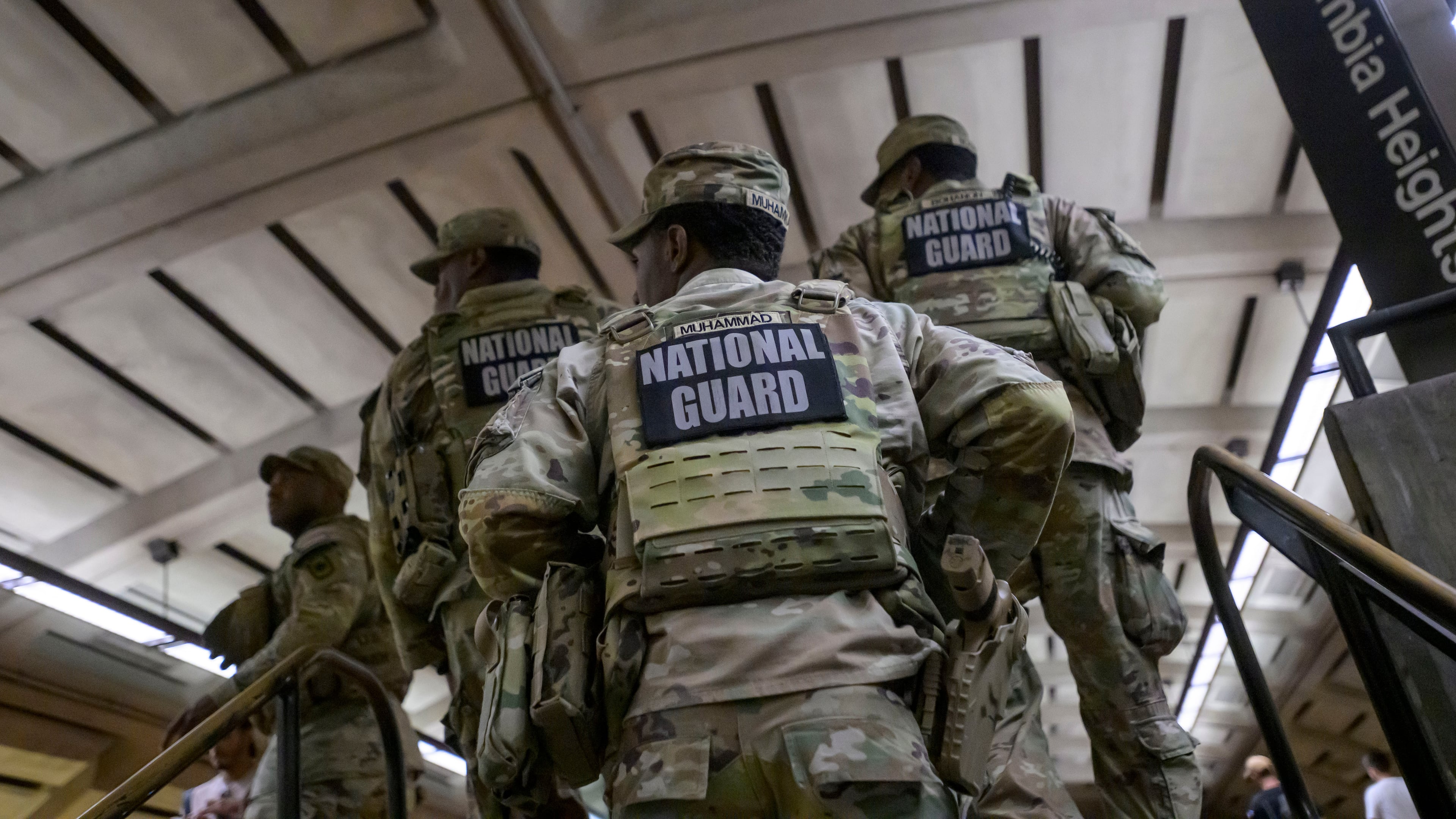 Members of the Arkansas National Guard continue their patrol after carrying an elderly woman in her wheelchair down the steps to the train platform due to an out-of-service elevator at the Columbia Heights metro station, Monday, Aug. 10, 2026, in Washington. (AP Photo/Rod Lamkey, Jr.)