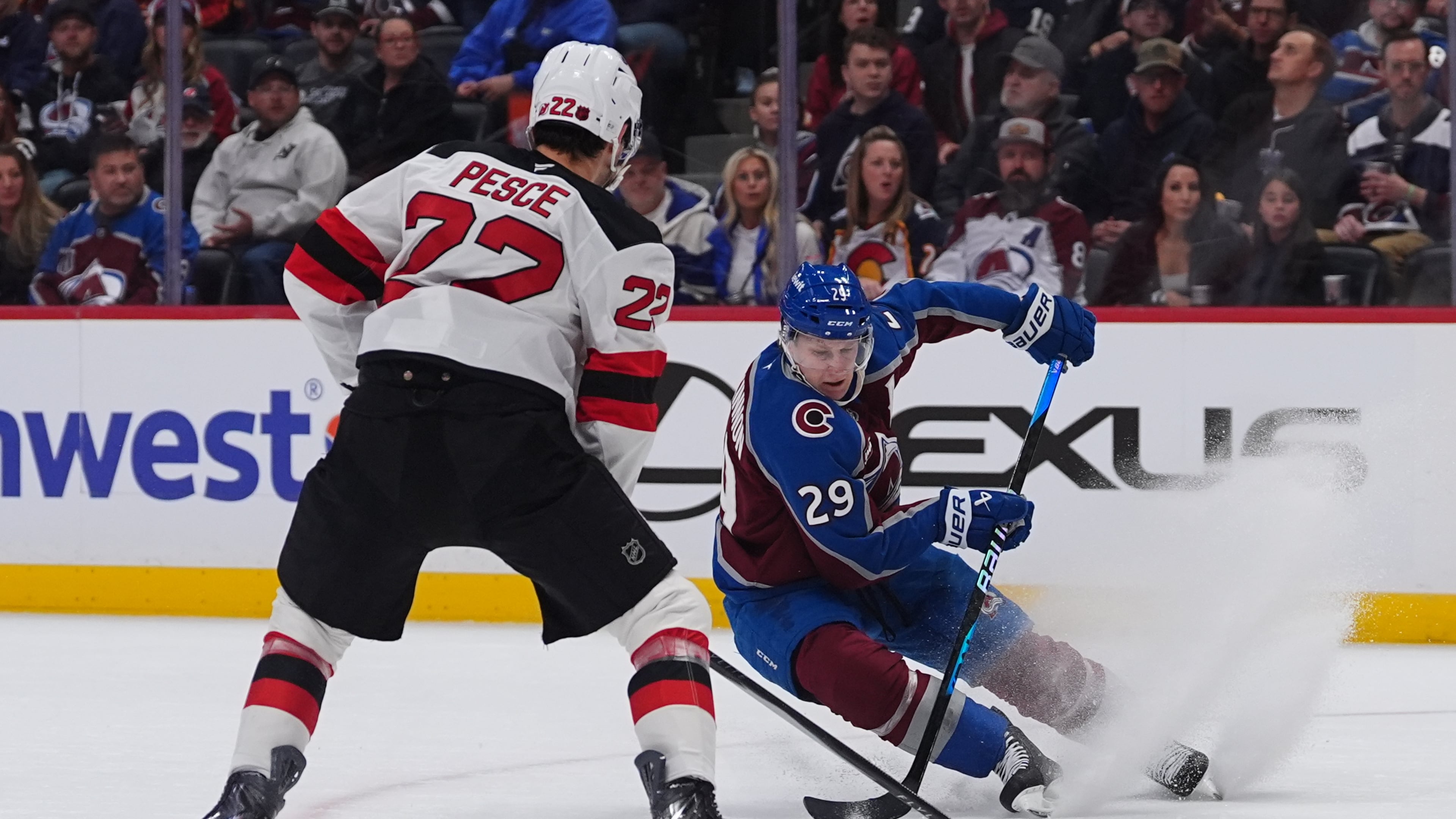Colorado Avalanche center Nathan MacKinnon, right, looks to pass the puck as New Jersey Devils defenseman Brett Pesce covers in the first period of an NHL hockey game Wednesday, Oct. 28, 2026, in Denver. (AP Photo/David Zalubowski)