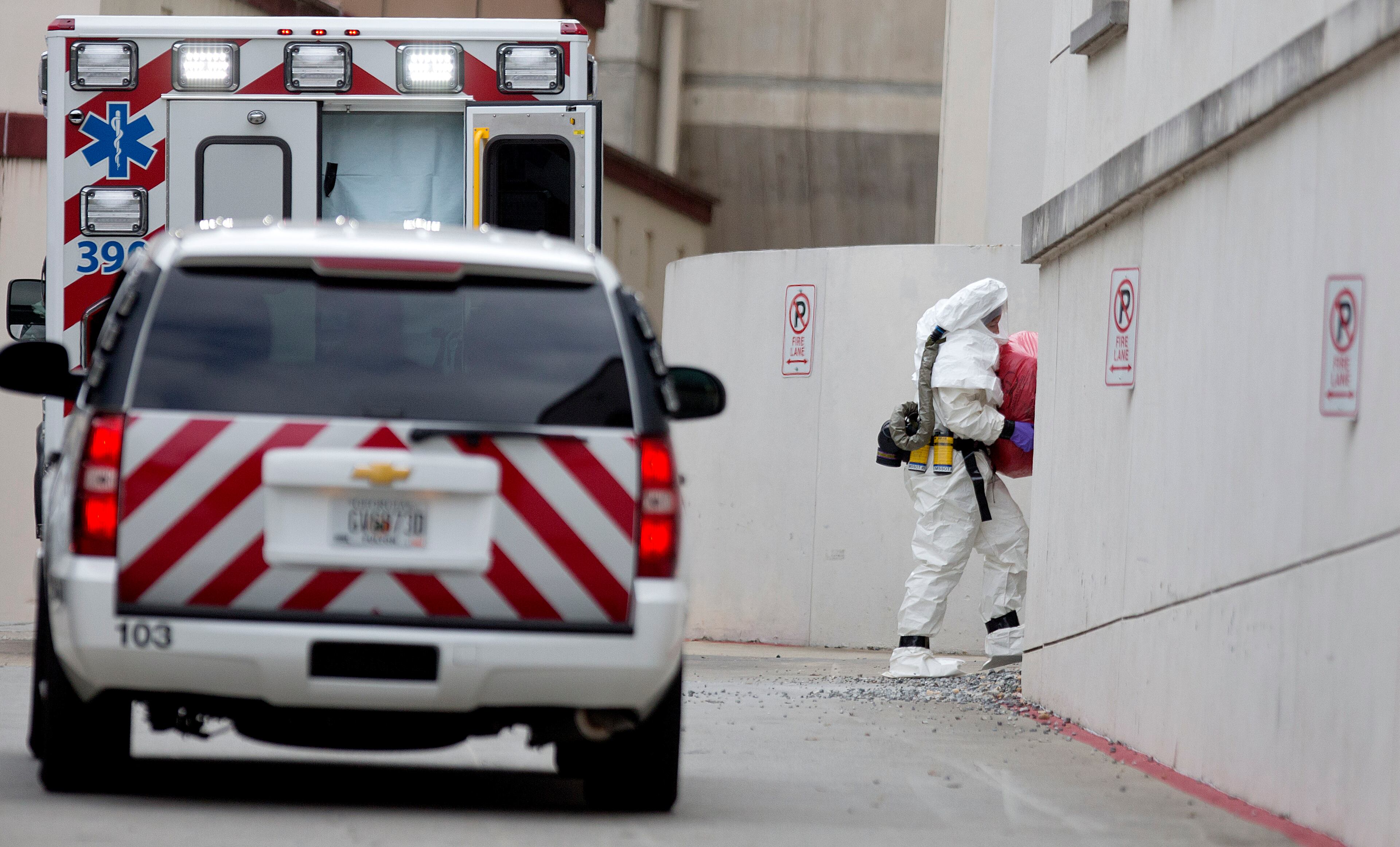 A person wearing a haz-mat suit carries a wrapped object out of an ambulance into Emory University Hospital after an ebola patient was taken in for treatment, Tuesday, Sept. 9, 2014, in Atlanta. The fourth American aid worker sickened with the Ebola virus arrived Tuesday morning for treatment at Emory University Hospital, where two others have been successfully treated. (AP Photo/David Goldman)