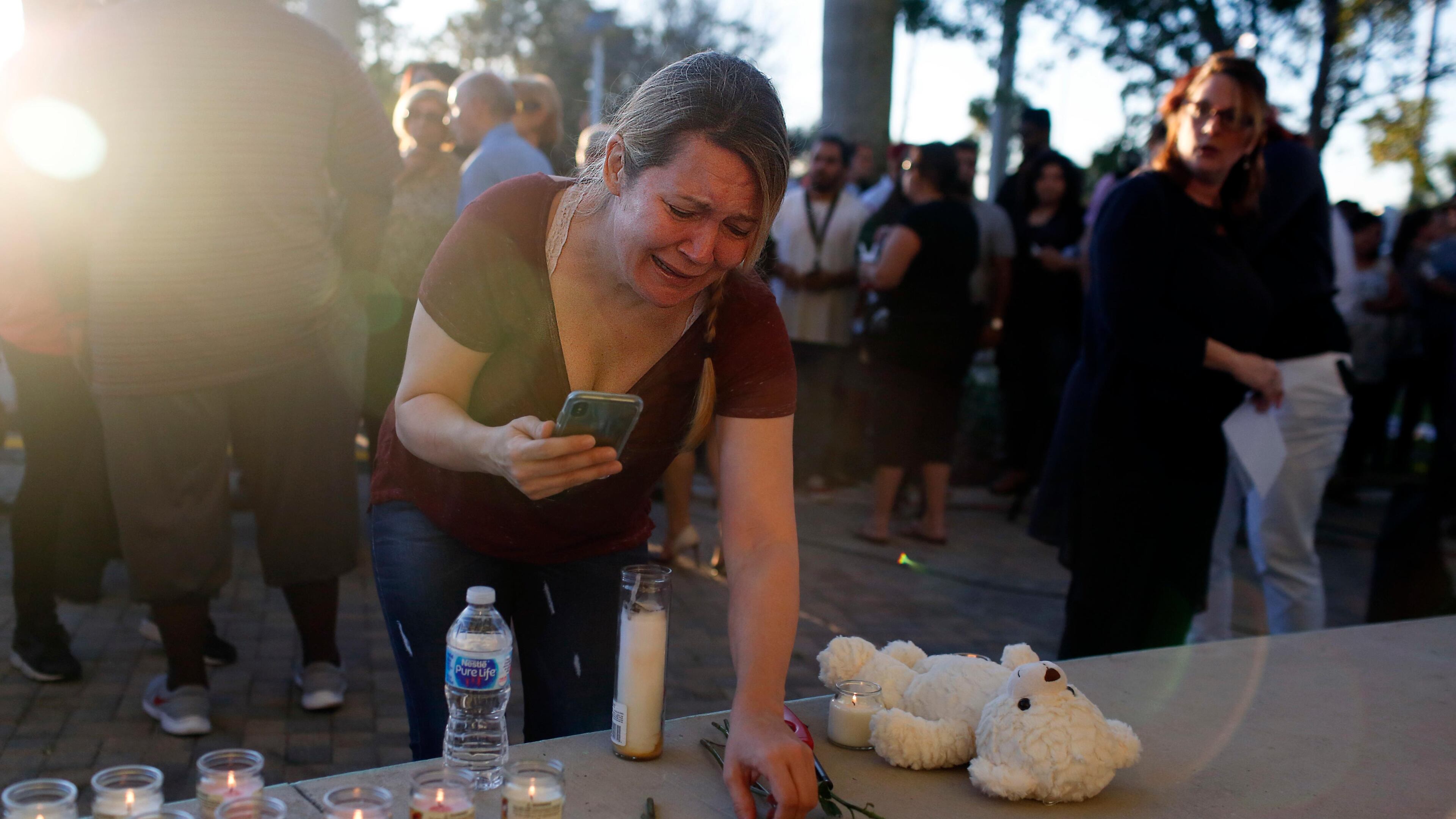 A woman places roses on a stage during a vigil at Pine Trails Park for the victims of the Wednesday shooting at Marjory Stoneman Douglas High School in Parkland, Fla., Thursday, Feb. 15, 2018. Nikolas Cruz, accused of using a semi-automatic rifle in a shooting at a Florida high school, confessed to carrying out the killing and carried extra ammunition in his backpack, according to a sheriff's department report released Thursday. (AP Photo/Brynn Anderson)