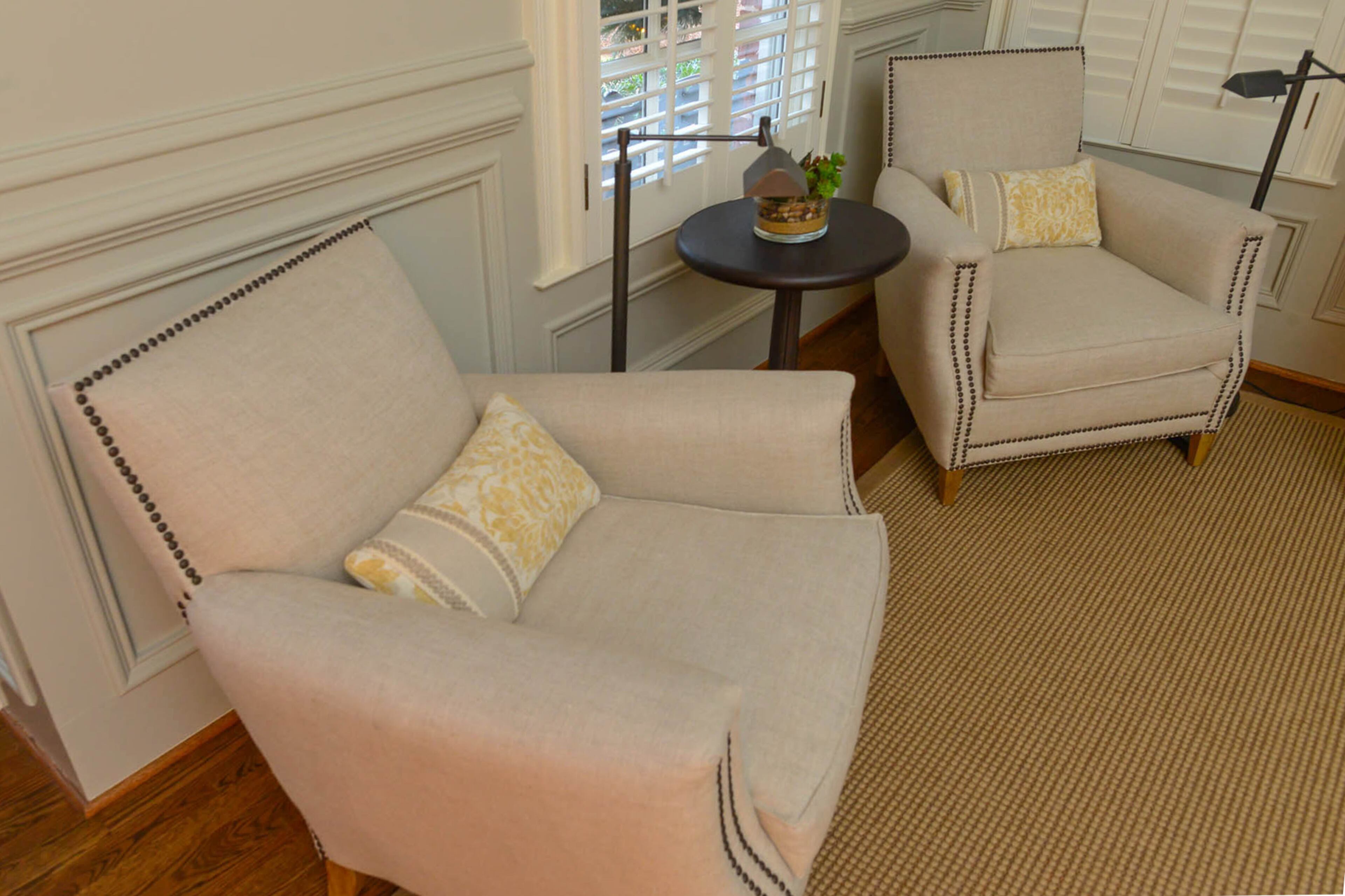 A pair of Marcel Upholstered Club Chairs from RH rest between a cocktail table in the parlor. The chairs, with brass nailhead trims, are modeled on French chairs of the 1930s and 1940s.