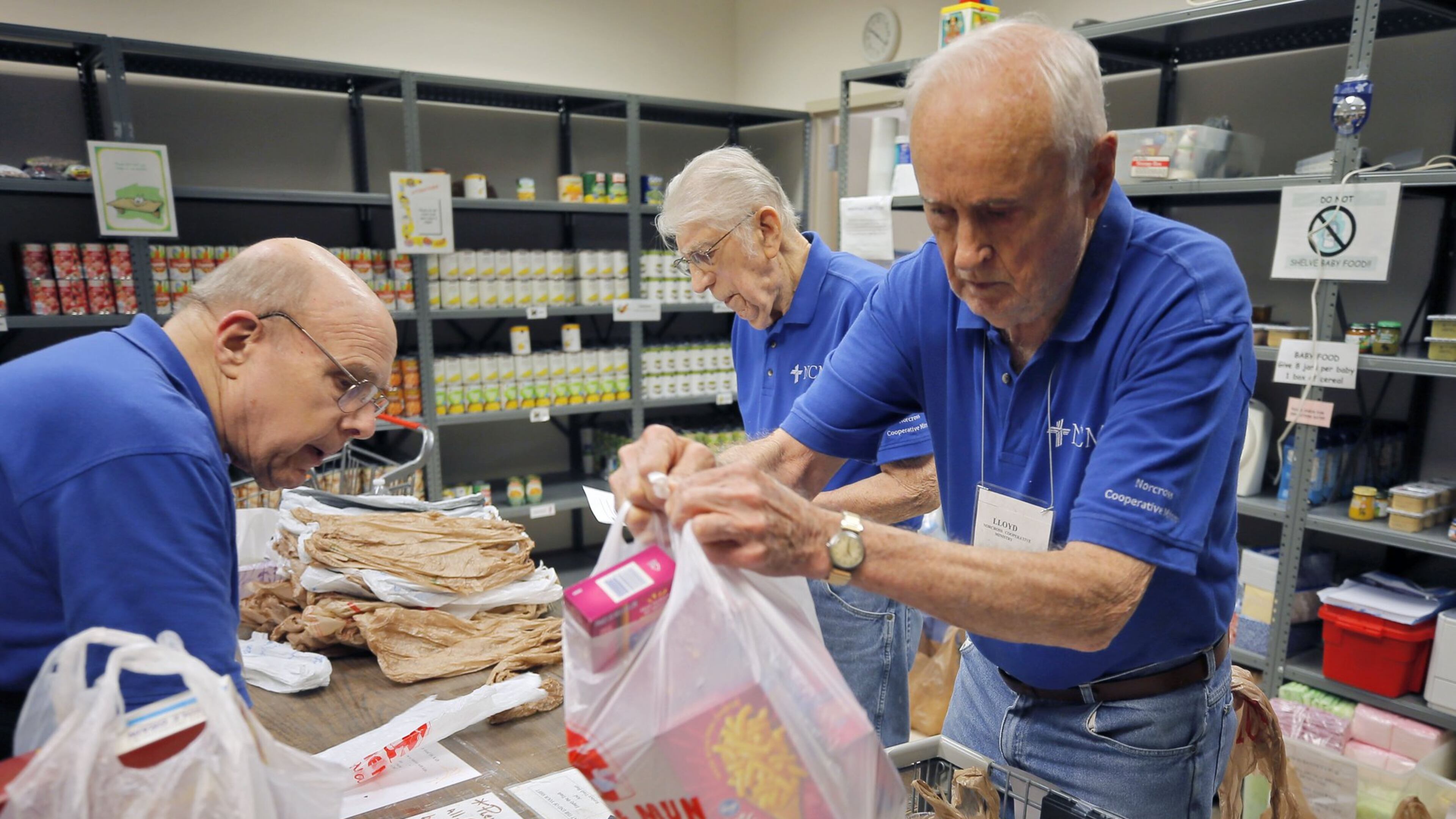 Volunteers John Lounsbury (from left), Ed Osowski and Lloyd Foster fill food orders at Norcross Cooperative Ministry, one of the busiest co-ops in Gwinnett County, on July 13, 2018. BOB ANDRES /BANDRES@AJC.COM