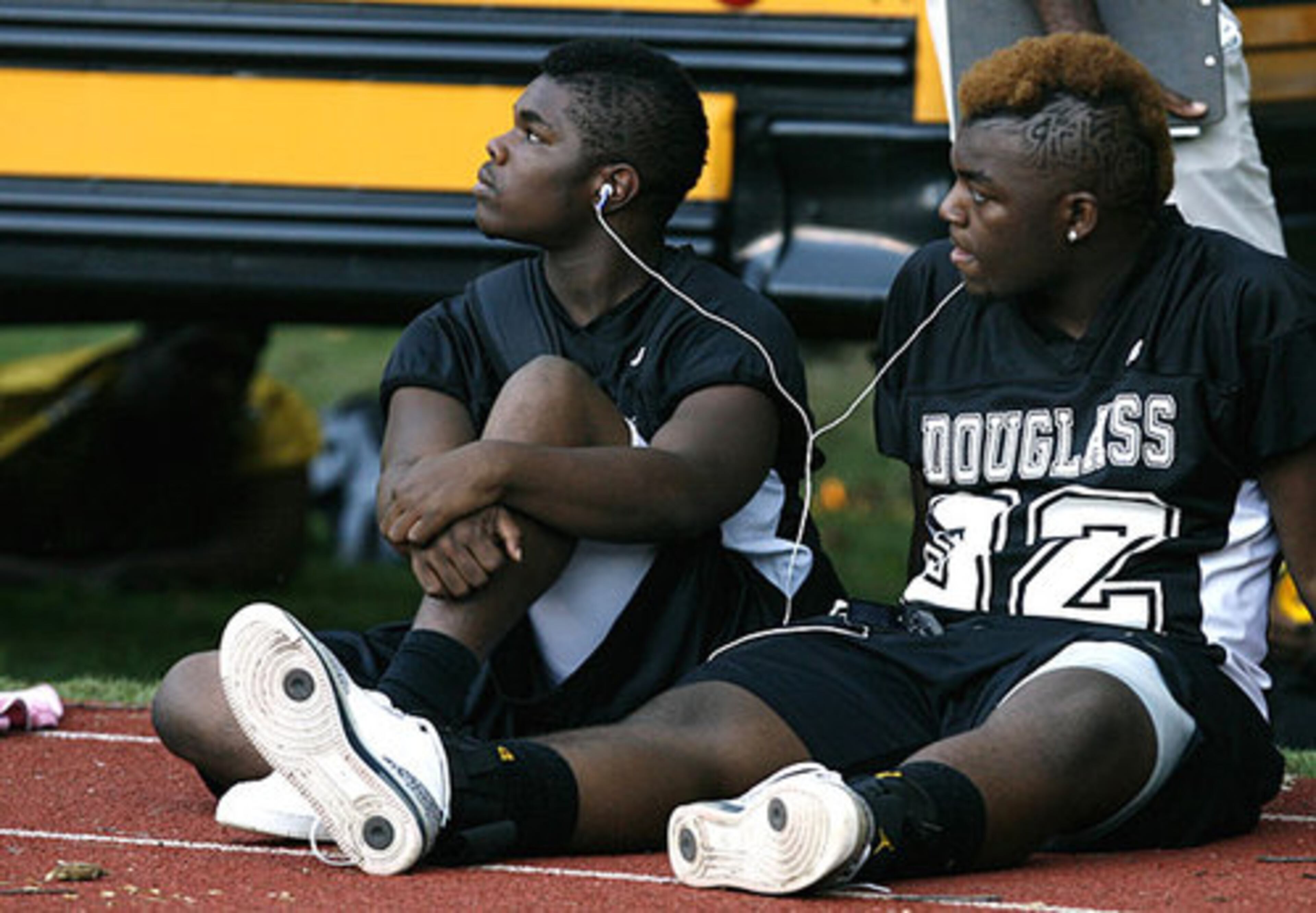 Douglass running backs Cameron Collins (left) and Timothy Morris share headphones to listen to Young Jeezy before the game against Chamblee at Chamblee Stadium on Friday.