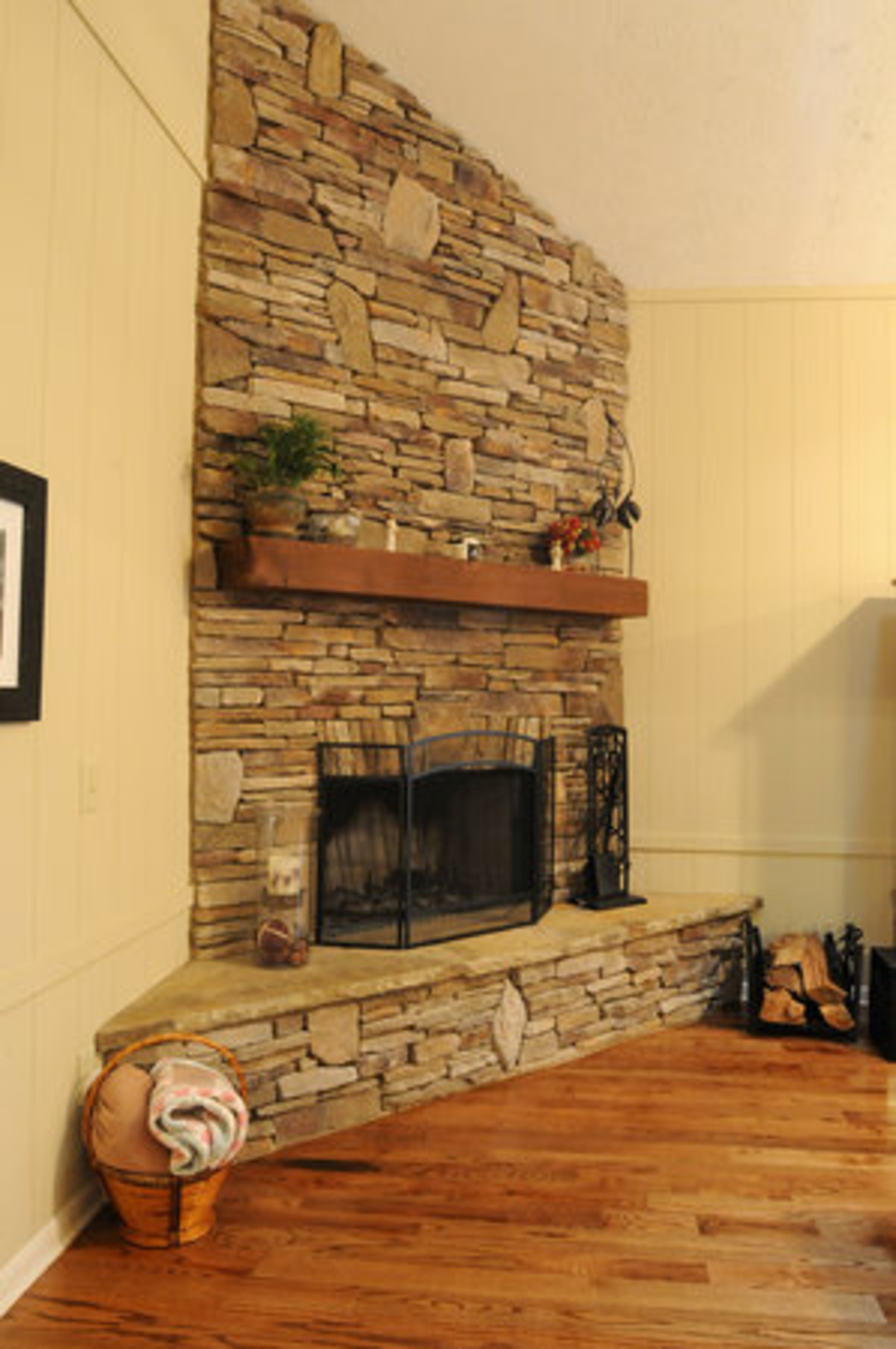 (The fireplace) "We completely ripped out the old fireplace and replaced it with a stacked-stone fireplace. We chose a light color because it balances the natural light in the room. Added photos of beach scenes to reflect her love of the ocean." She said.