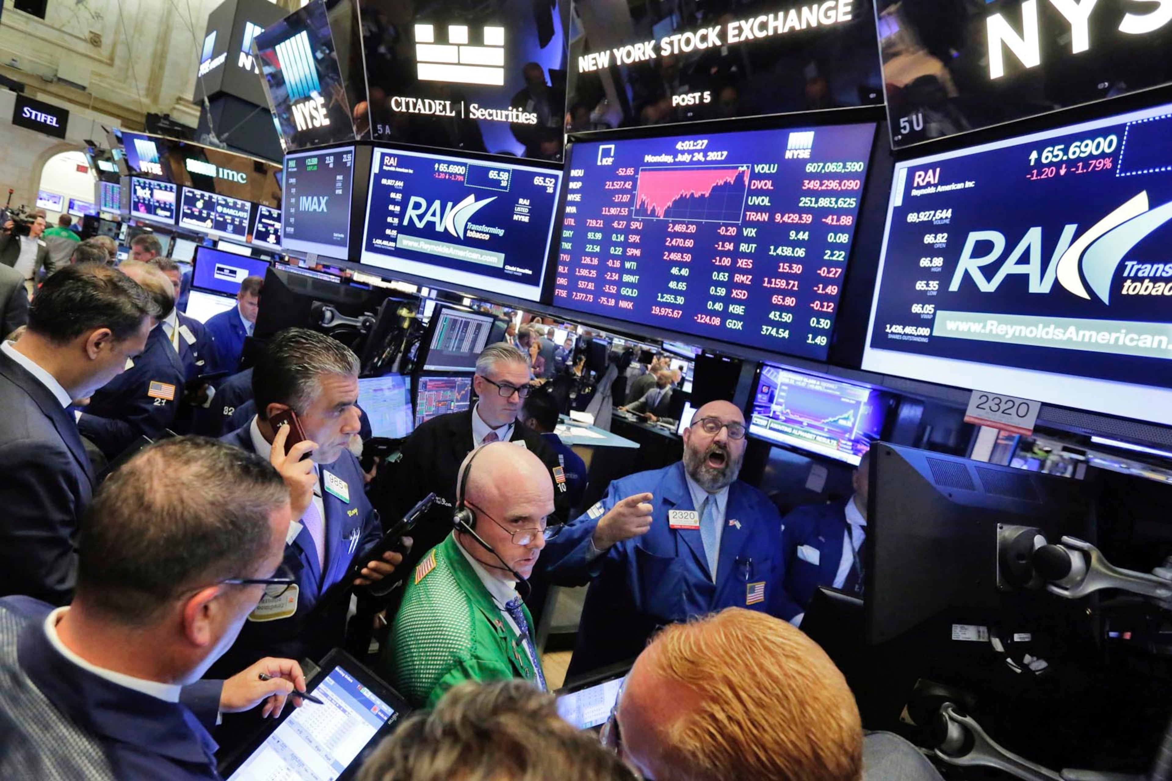 Specialist Peter Giacchi, background center, handles the close of trading of Reynolds American on the floor of the New York Stock Exchange, Monday, July 24, 2017. (AP Photo/Richard Drew)