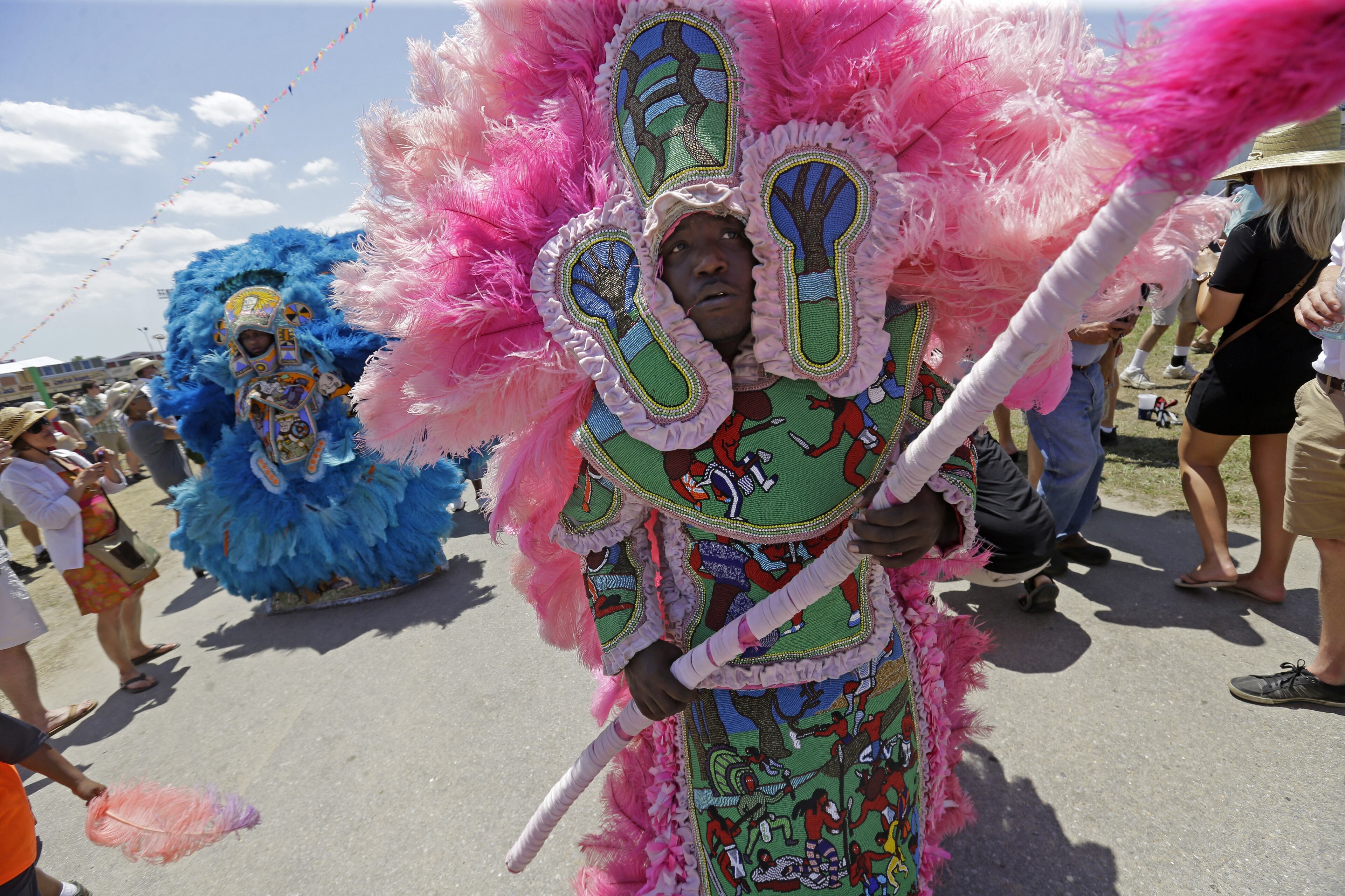 Members of the New Orleans Mardi Gras Indian Rhythm Section, with the Algiers Warriors and Golden Comanche Mardi Gras Indians, march in a second line parade at the New Orleans Jazz and Heritage Festival in New Orleans, Friday, May 1, 2015. (AP Photo/Gerald Herbert)