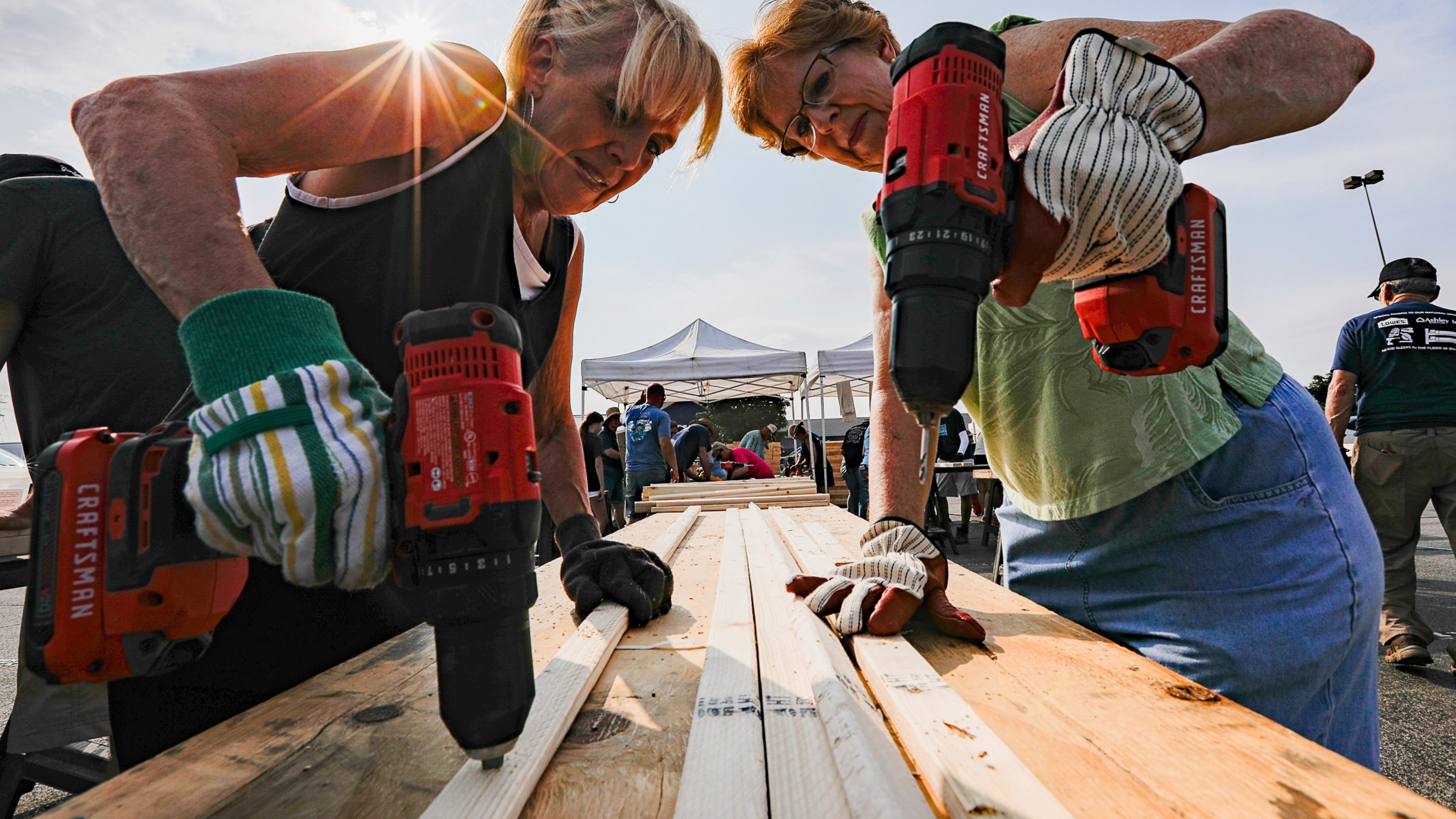 FILE - Volunteers Susan Chastain and Jenny Allen drill holes into two-by-fours during Bunks Across America, a non-profit event to build bunk beds for children in need at Lowe's, June 12, 2021 in East Brainerd, Tenn. (Troy Stolt/Chattanooga Times Free Press via AP, File)