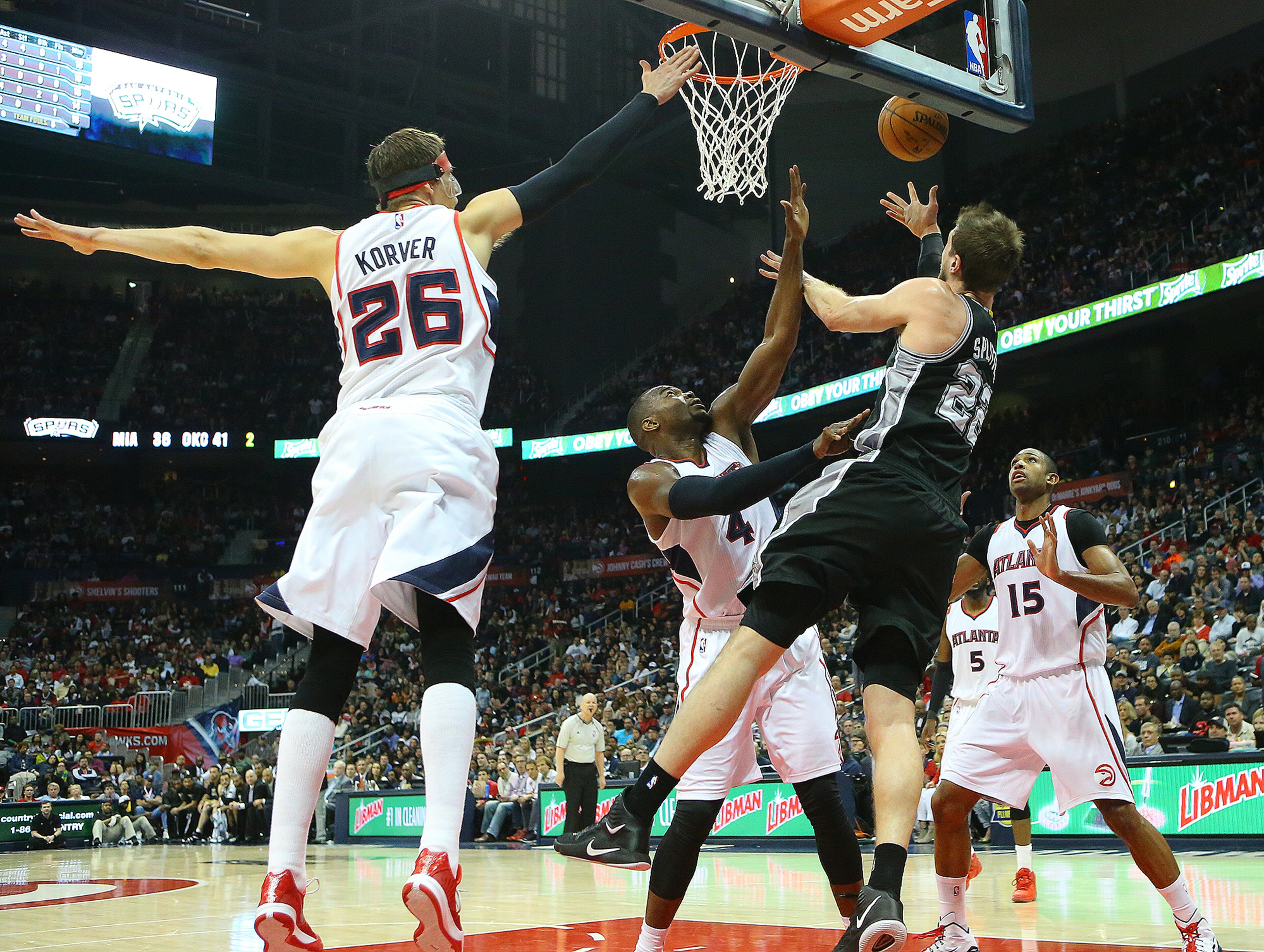 Spurs forward Tiago Splitter lays it up for two points from behind the rim despite a triple team by Hawks defenders Kyle Korver (from left), Paul Millsap and Al Horford during a basketball game on Sunday, March 22, 2015, in Atlanta. Curtis Compton / ccompton@ajc.com