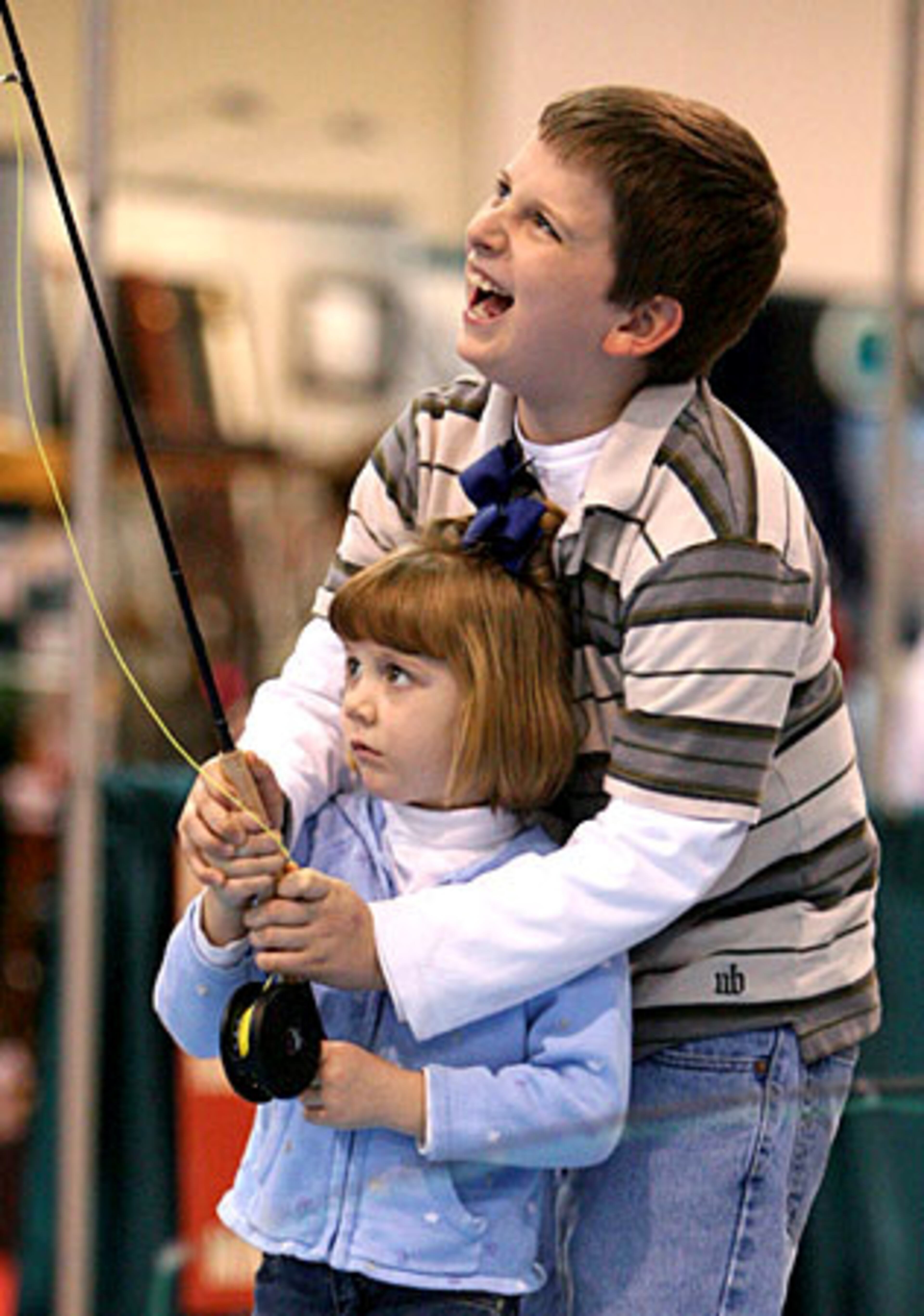 Zachary Derr, 11, of Canton, laughs as he helps his cousin Gracie Dixon, 5, also of Canton, as they learn to cast.