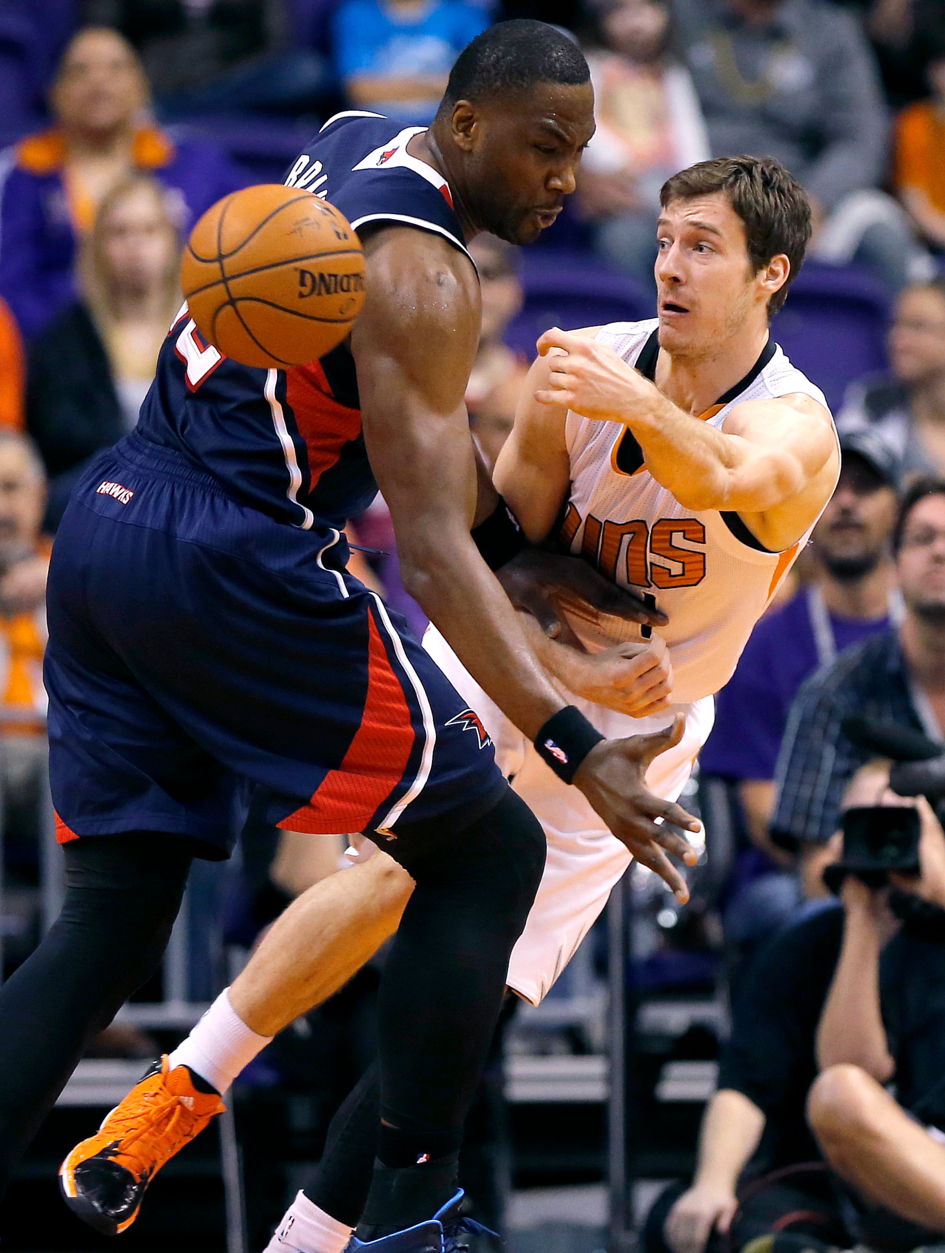 Phoenix Suns' Goran Dragic, right, of Slovenia, dishes around Atlanta Hawks' Elton Brand, left, during the first half of an NBA basketball game Sunday in Phoenix. (AP Photo/Matt York)