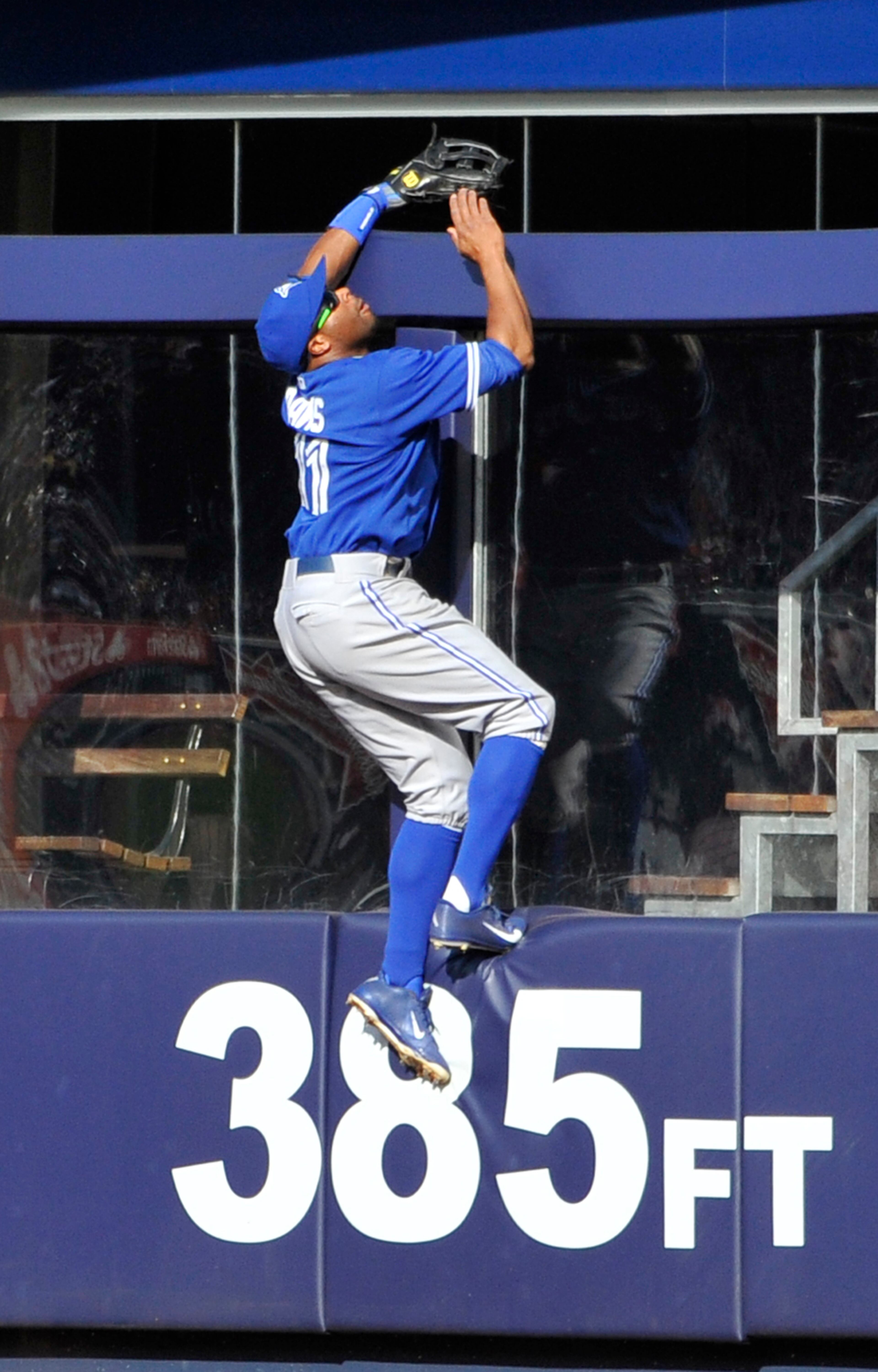 Toronto Blue Jays right fielder Rajai Davis climbs the outfield wall unsuccessfully to try and snag a three-run home run hit by New York Yankees' Travis Hafner on April 27, 2013 in New York. (AP Photo/Kathy Kmonicek)