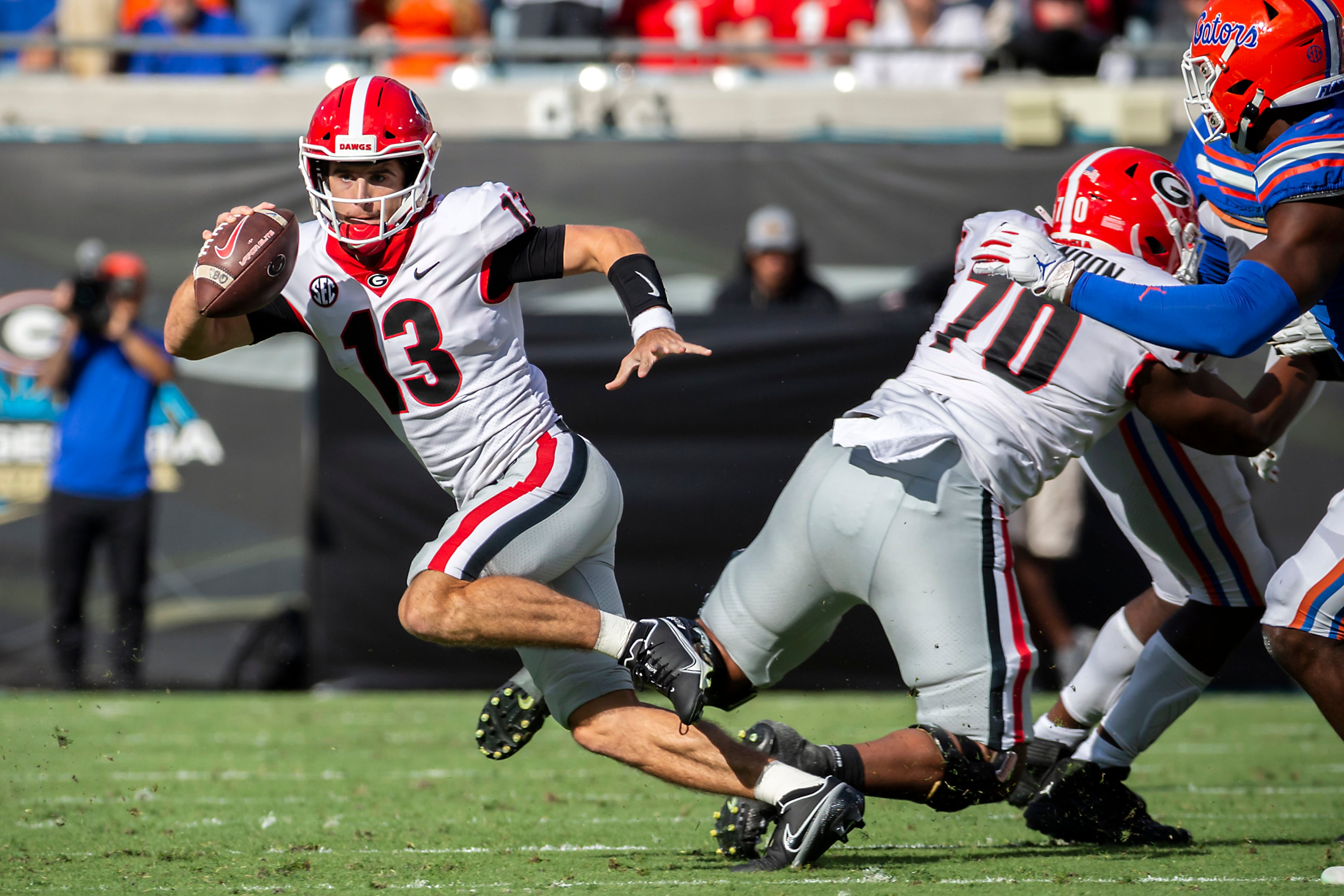 Georgia quarterback Stetson Bennett (13) scrabbles out of the pocket during the first half of an college football game against Florida, Saturday, Oct. 30, 2021, in Jacksonville, Fla. (Stephen B. Morton/Atlanta Journal-Constitution)