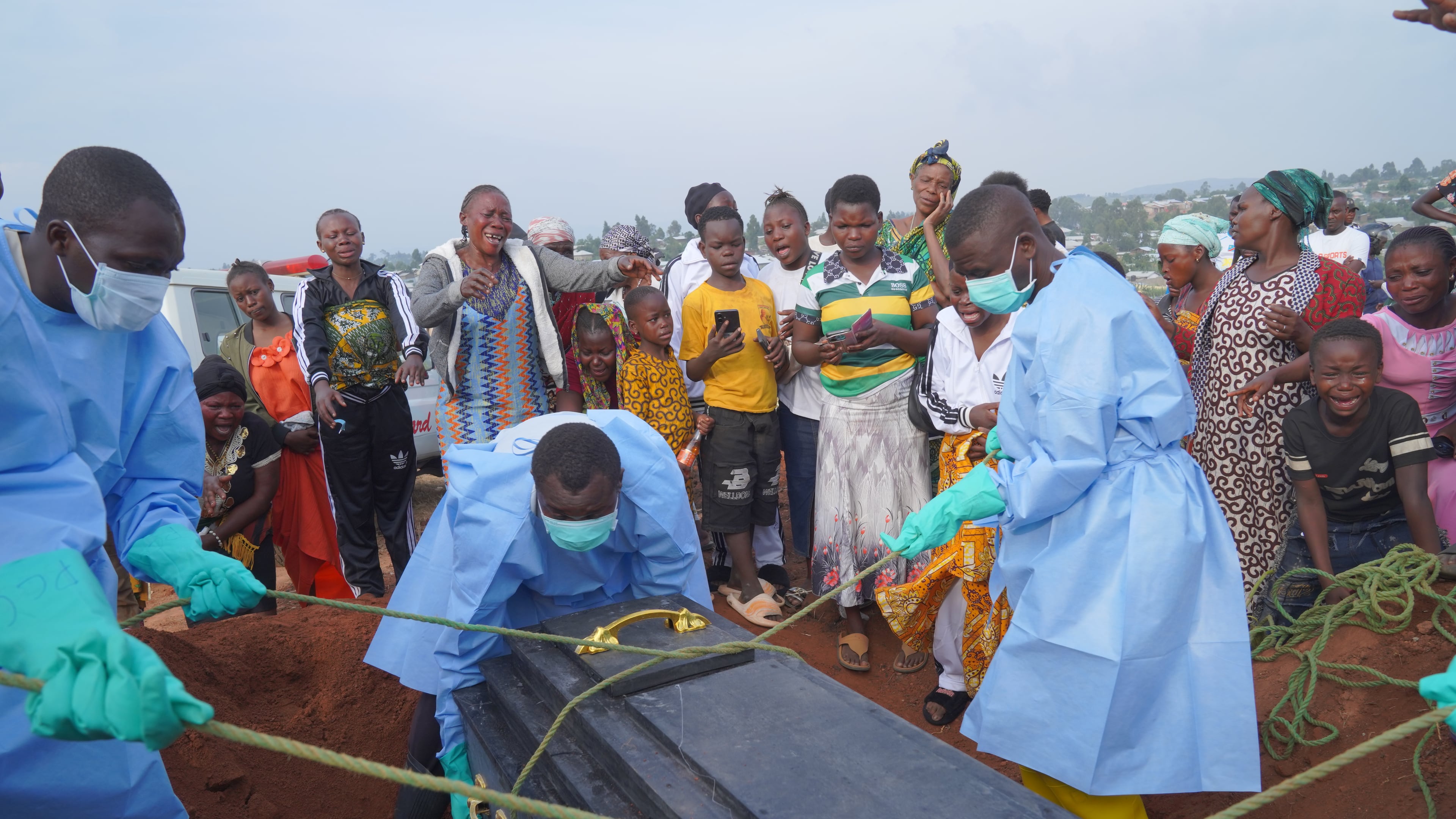 People dressed in protective gear lower into a grave the coffin containing the remains of Jeannine Katusabe, who died of Ebola, during a burial service in Bunia, Ituri province, eastern Congo, Tuesday, Aug. 11, 2026. (AP Photo/Dieudonne Dirole)