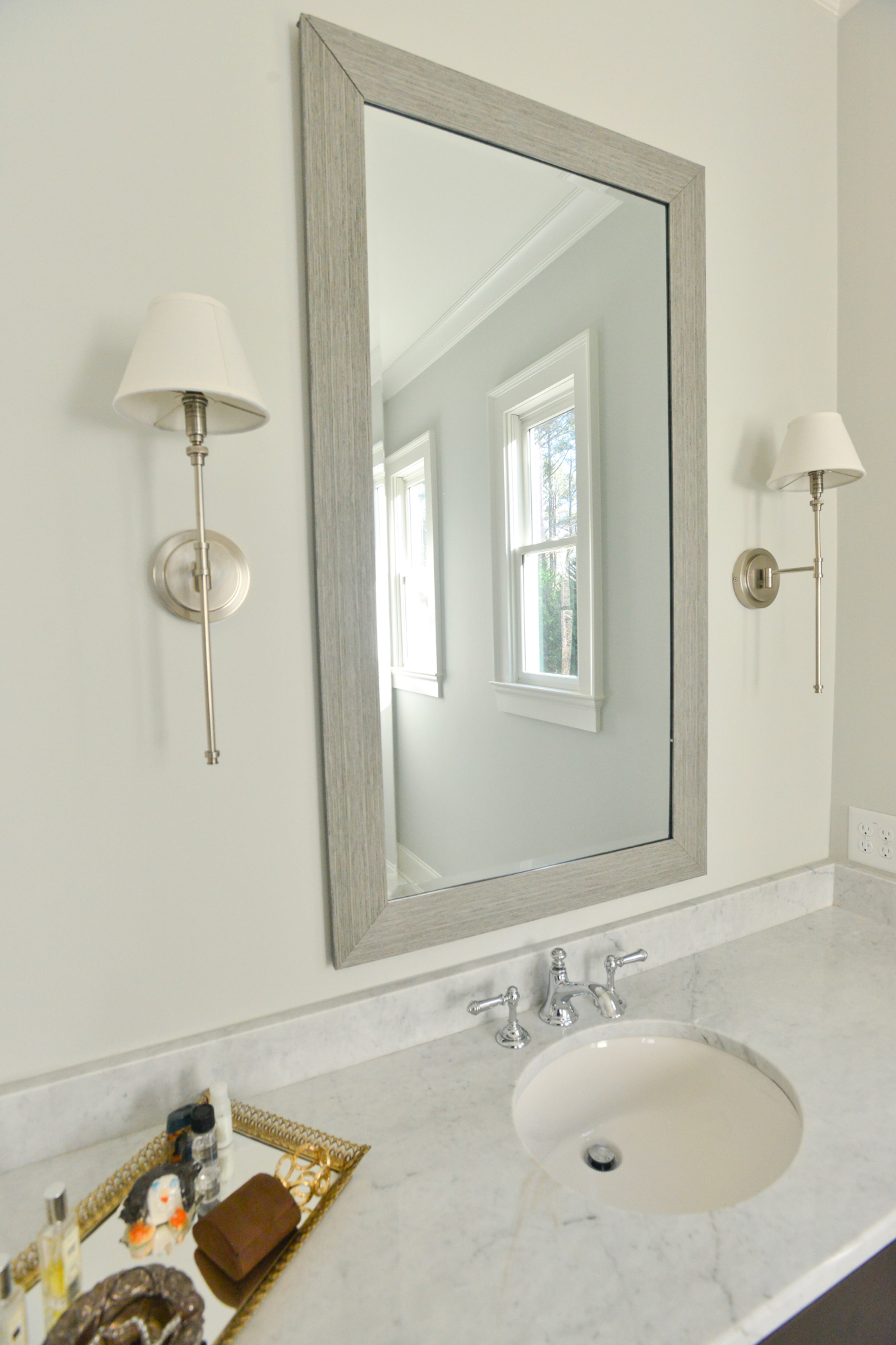 The homeowners continued the Carrera marble from the master bath floors to the countertops. Elegant antique pewter sconces from RH Baby & Child flank the bathroom's mirror. Text by Lori Johnston and Keith Still/Fast Copy News Service.