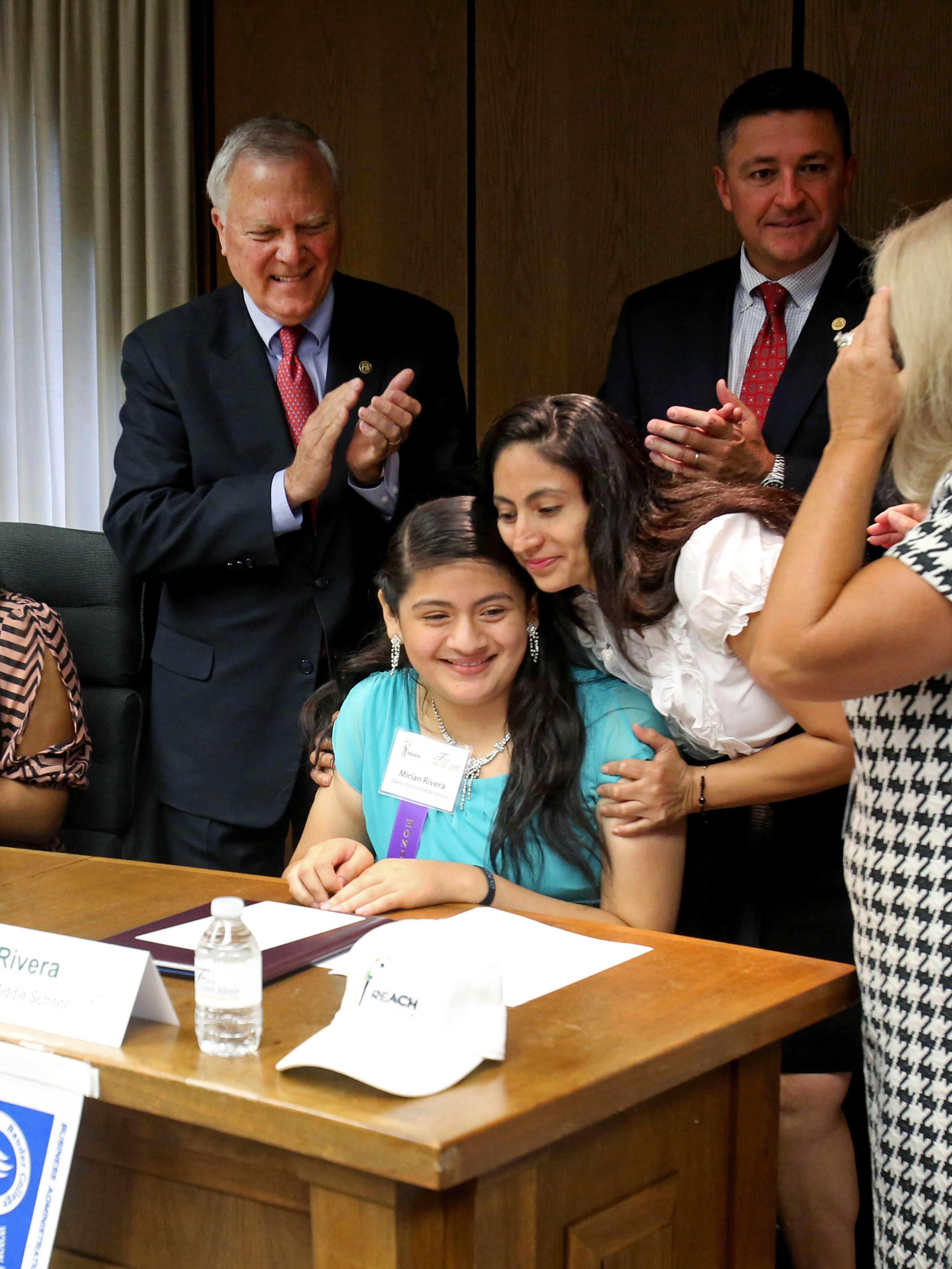 Gregoria Banuelos, right, celebrates with her daughter Mirian Rivera, a student at Elkins Pointe Middle, after Mirian signed during the REACH Statewide Signing Day program.
