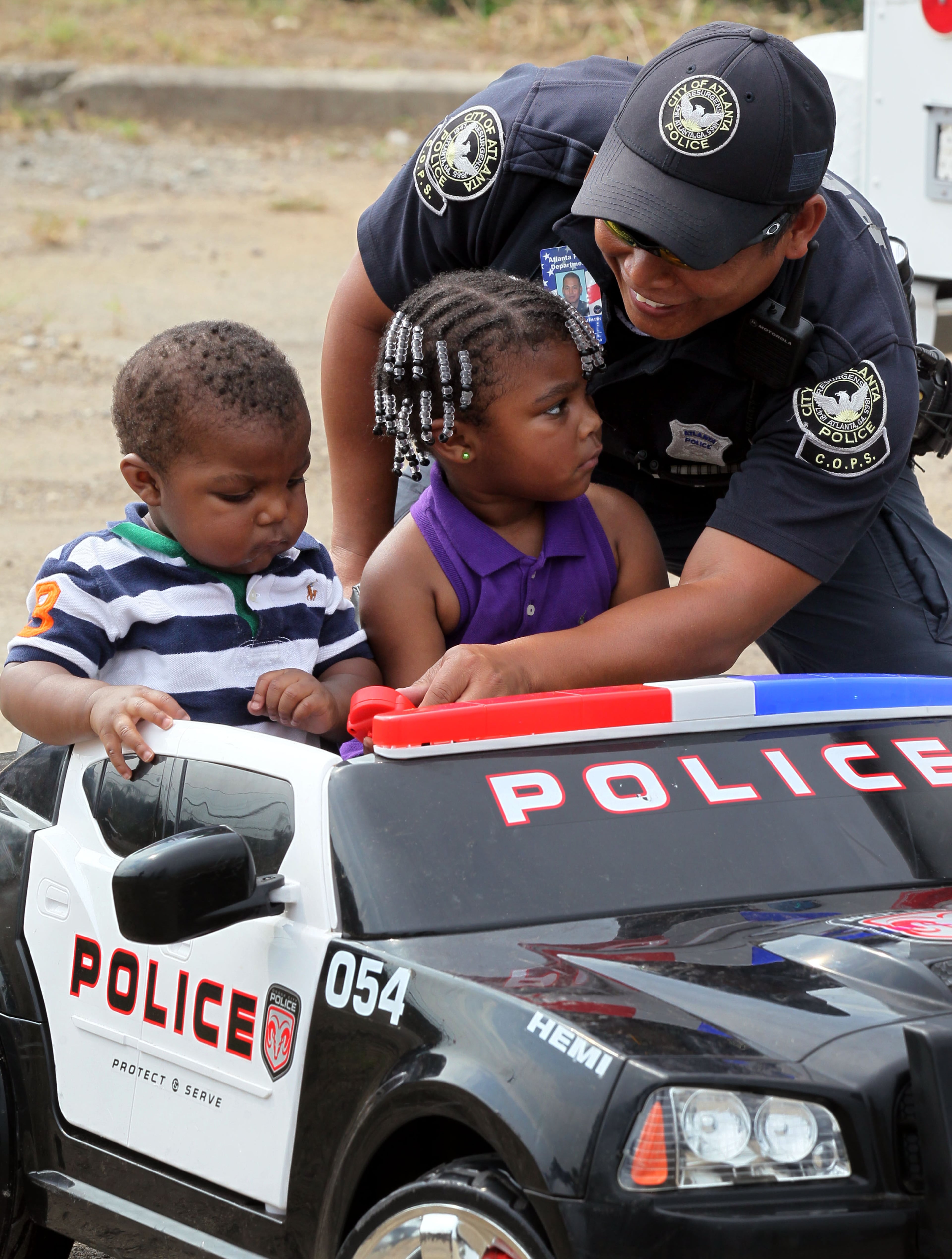 Atlanta COPS Unit Officer K. Thongkoth (right) showed 1-year-old Ja'Kahri Howard & his sister Khaniya (3) a minipolice car during the 2013 National Night Out in Atlanta on Tuesday, Aug. 6, 2013.