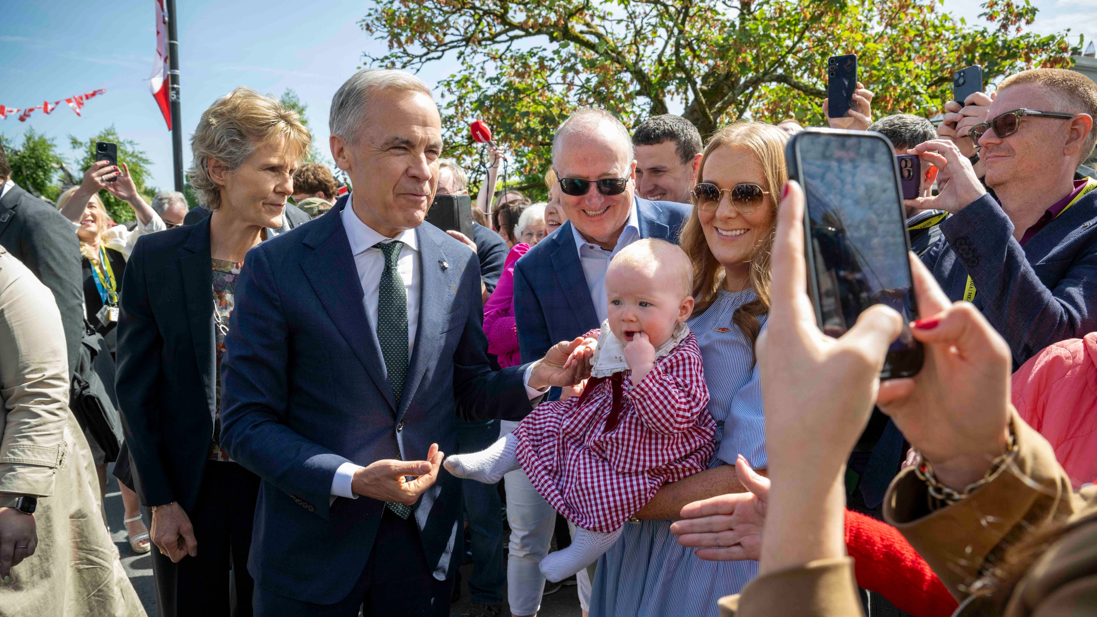 Canadian Prime Minister Mark Carney, front left, has a picture taken with Lily Meskil, 9 months and her grandfather Ger Basquel and mother Rachel Basquel, during a visit to Aughagower, Ireland, Sunday, June 14, 2026. (Andrew Downes/PA via AP)