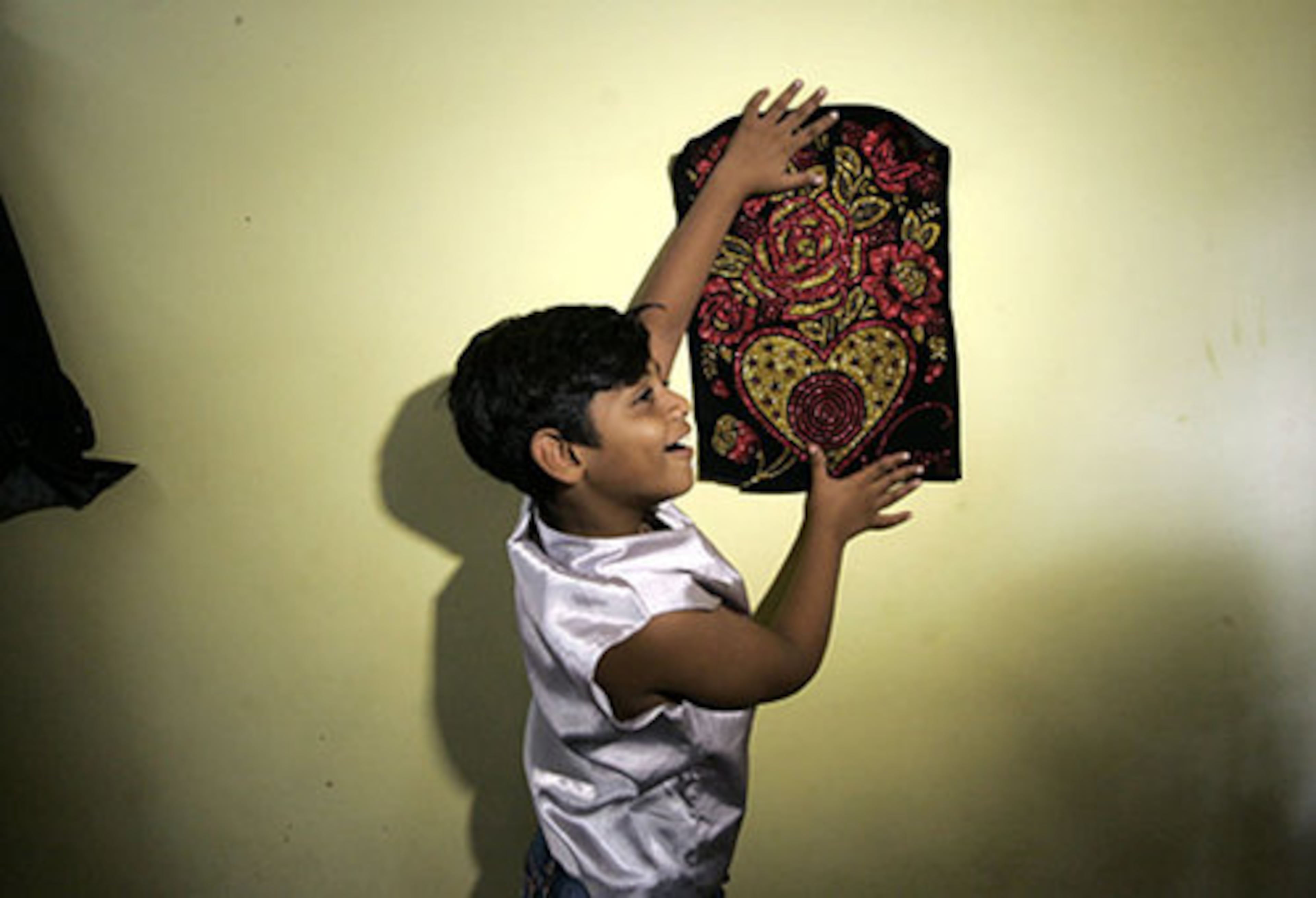 "Slumdog Millionaire" child star Azharuddin Mohammed Ismail, 10, places a showpiece on a wall of his new home. He played the youngest version of Salim, brother of main character Jamal, the character who goes from the slums to a a spot on India's version of 'Who Wants to be a Millionaire?'