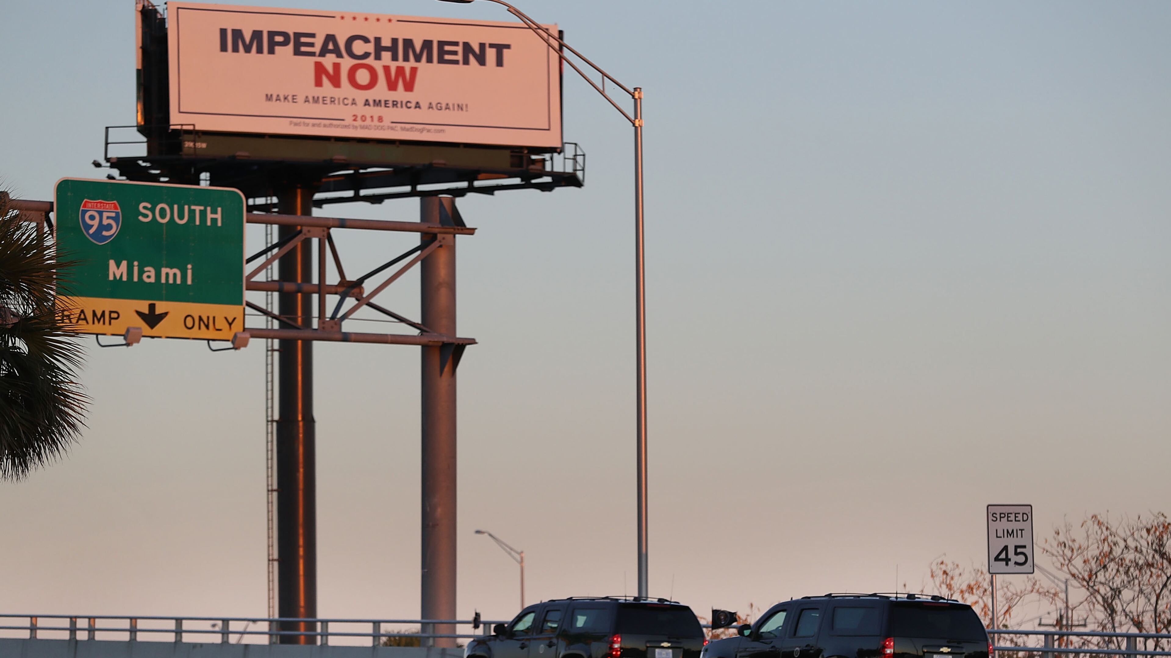 Vehicles from the motorcade carrying President Donald Trump pass a billboard reading: 'Impeachment Now Make America America Again!' as he is driven to Mar-A-Lago on March 23, 2018 in West Palm Beach, Fla. (Photo by Joe Raedle/Getty Images)