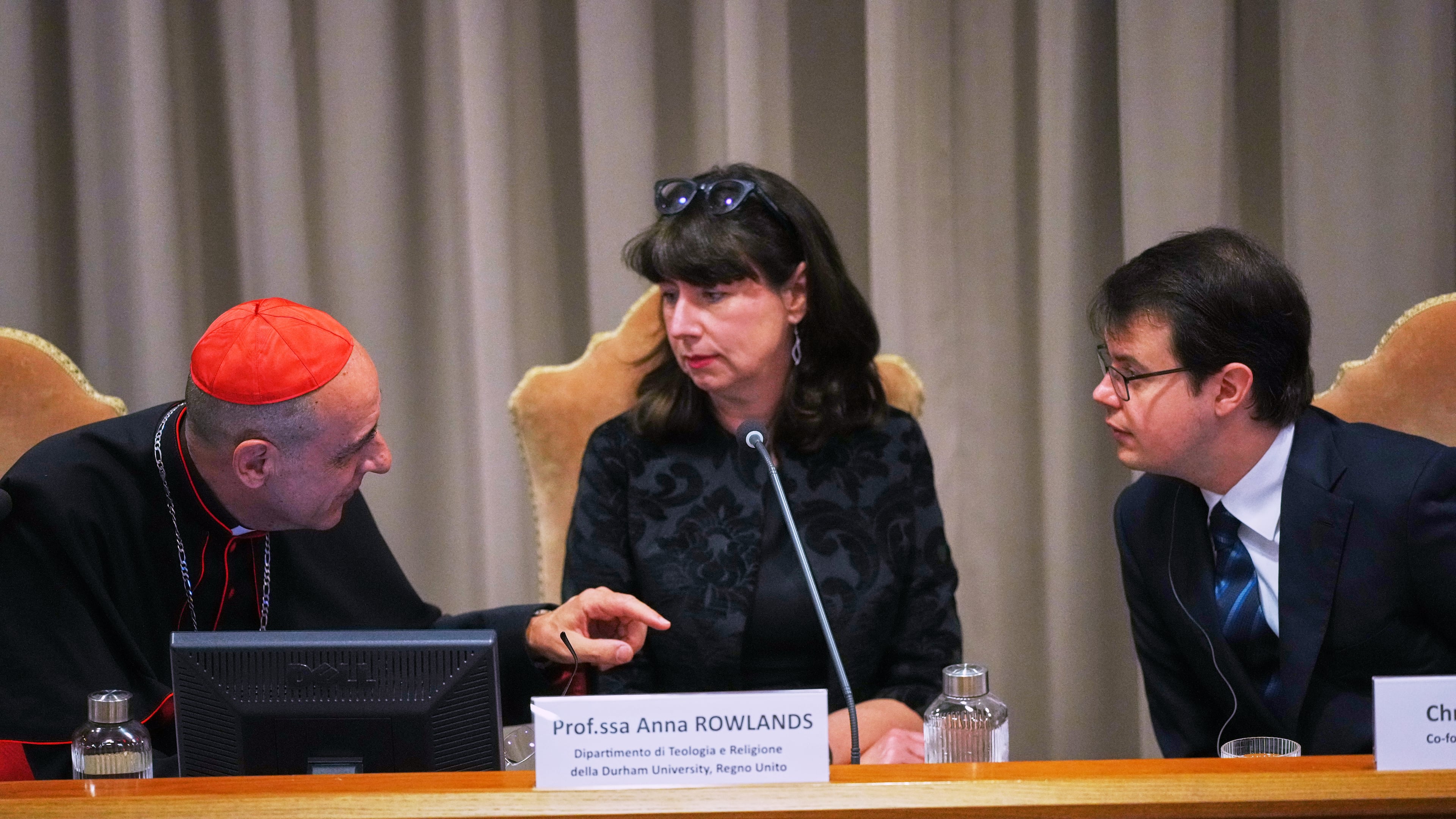 FILE - From left, Cardinal Víctor Manuel Fernández, prefect of the Dicastery for the Doctrine of the Faith, talks with theologian Anna Rowlands, and Anthropic co-founder Christopher Olah during the presentation of Pope Leo XIV's first encyclical, "Magnifica humanitas: On Safeguarding the Human Person in the Time of Artificial Intelligence," at the Vatican, May 25, 2026. (AP Photo/Alessandra Tarantino, File)