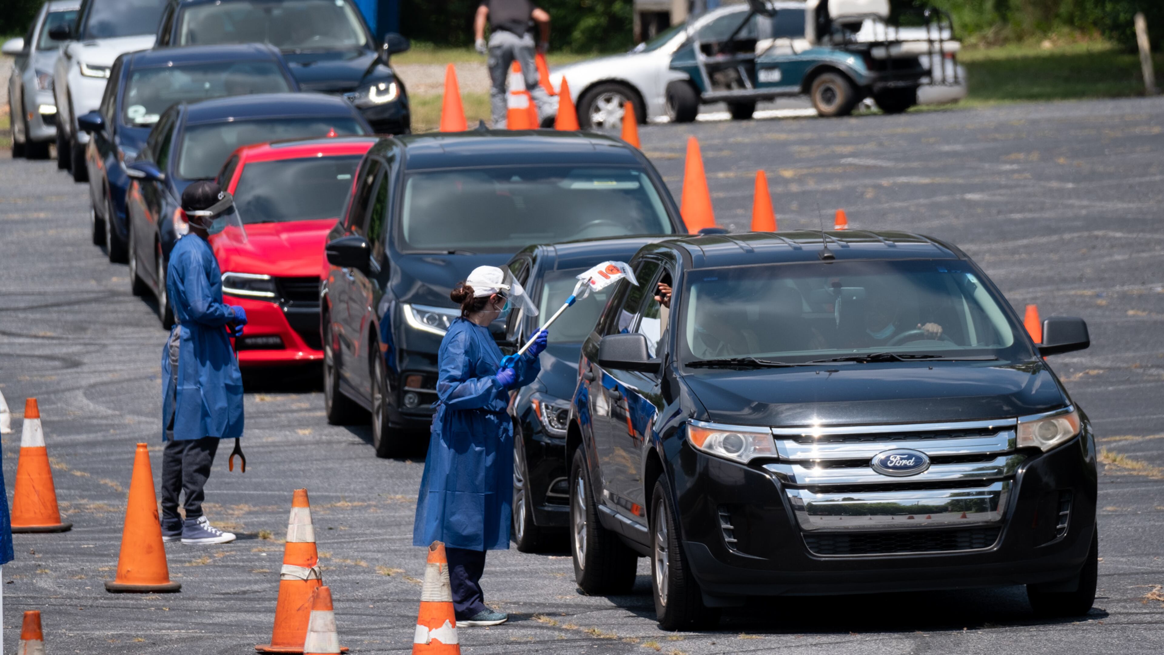 Workers at a CORE testing site at Antioch Baptist Church North in Northwest Atlanta collect covid-19 tests from a line of cars that disappears and wraps around the block Thursday afternoon July 16, 2020. Ben Gray for the Atlanta Journal-Constitution