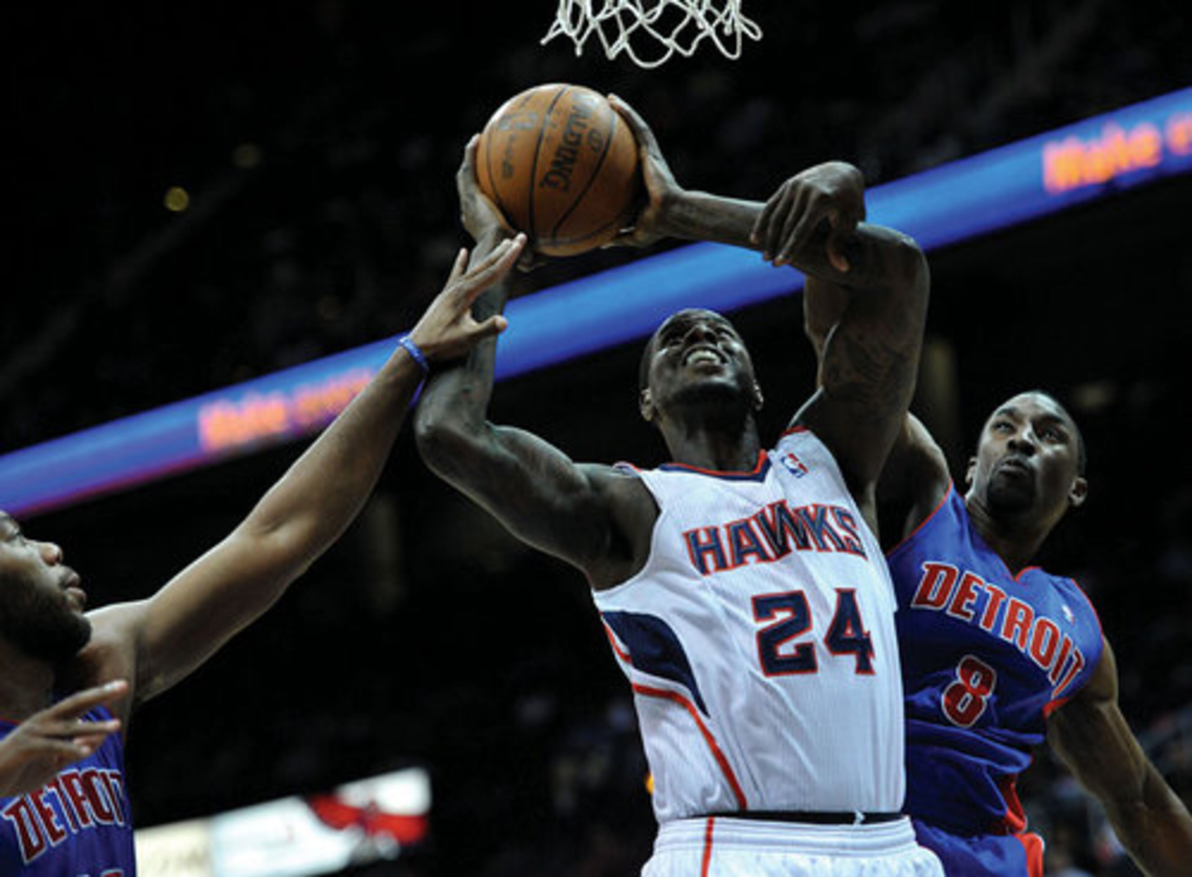 Hawks player Marvin Williams (center) is fouled by Ben Gordon (right) as Greg Monroe (left) also tries to stop him.