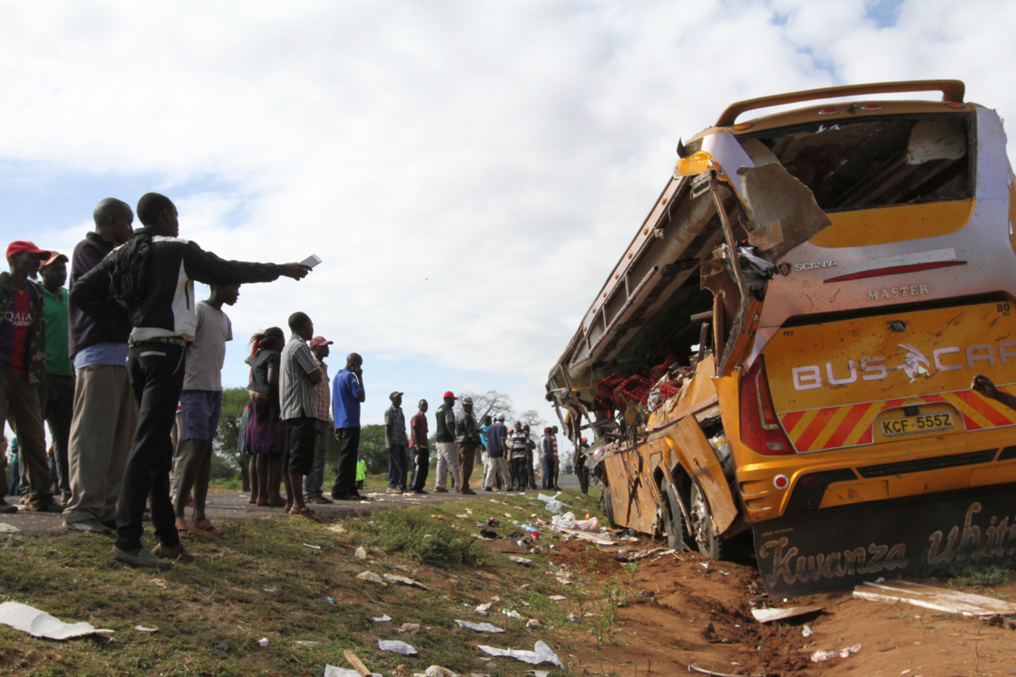 Kenyans look at the wreckage of a Buscar Bus Company vehicle that was involved in a road accident at Kambuu area in Makueni, along the Nairobi-Mombasa highway Tuesday, April 25. 2017. Kenyan police say 27 people have been killed in a collision between a passenger bus and a trailer truck. (AP Photo)