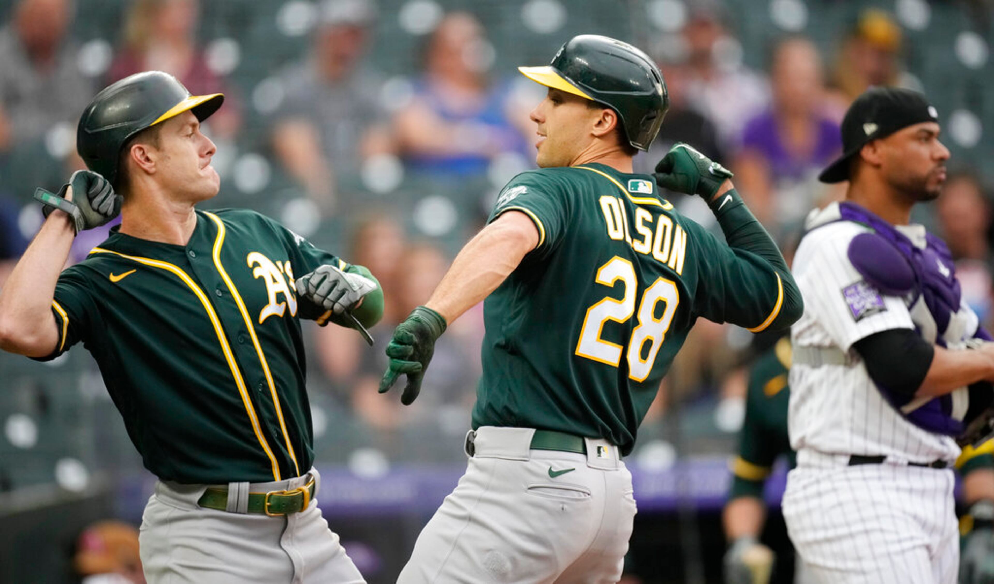 Oakland Athletics' Mark Canha, left, celebrates with Matt Olson who crosses home plate after hitting a two-run home run off Colorado Rockies starting pitcher Kyle Freeland in the first inning of a baseball game Saturday, June 5, 2021, in Denver. (AP Photo/David Zalubowski)