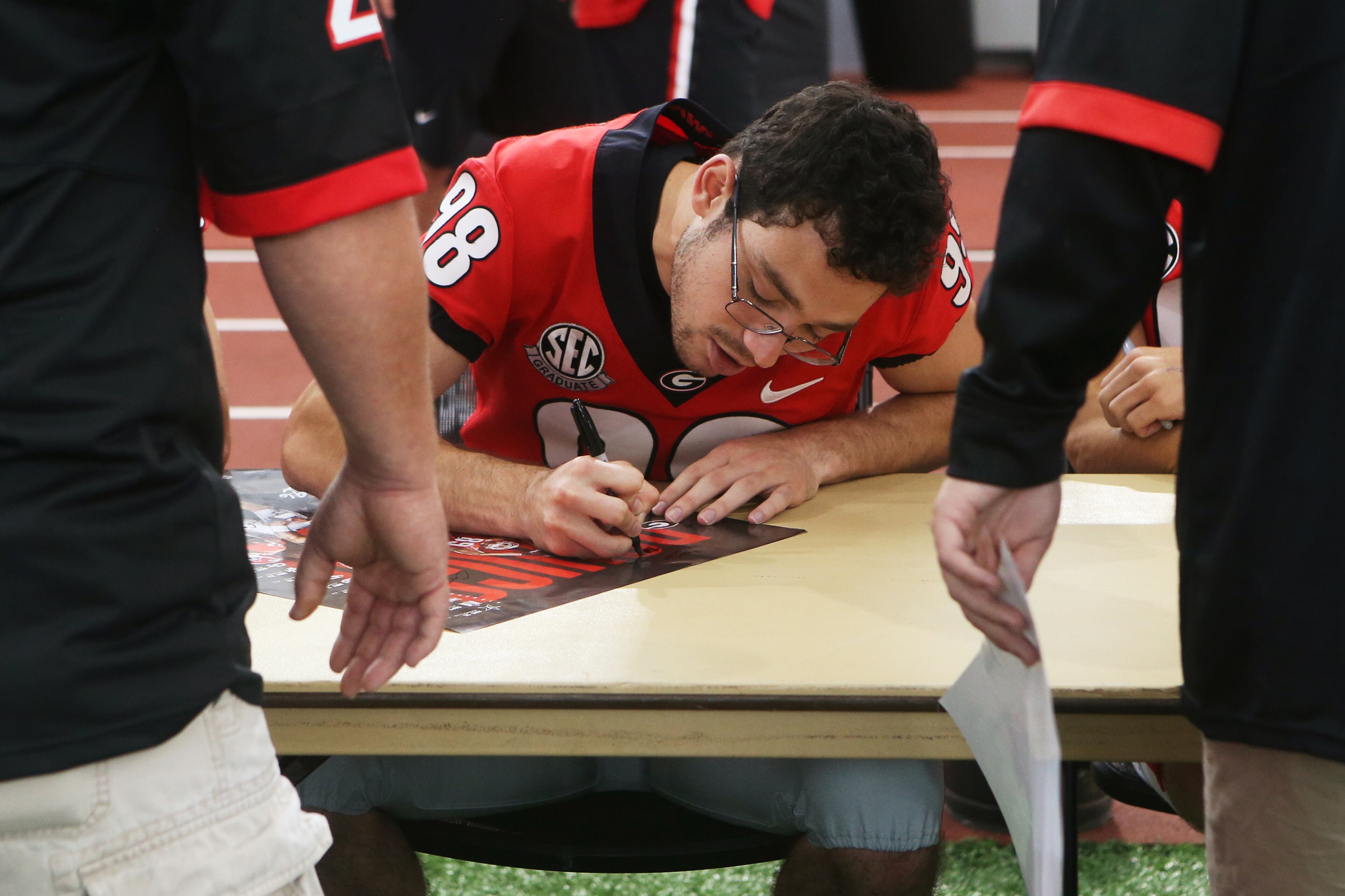 Kicker Rodrigo Blackenship signs a poster during UGA Fan Day. Christina Matacotta/Christina.Matacotta@ajc.com