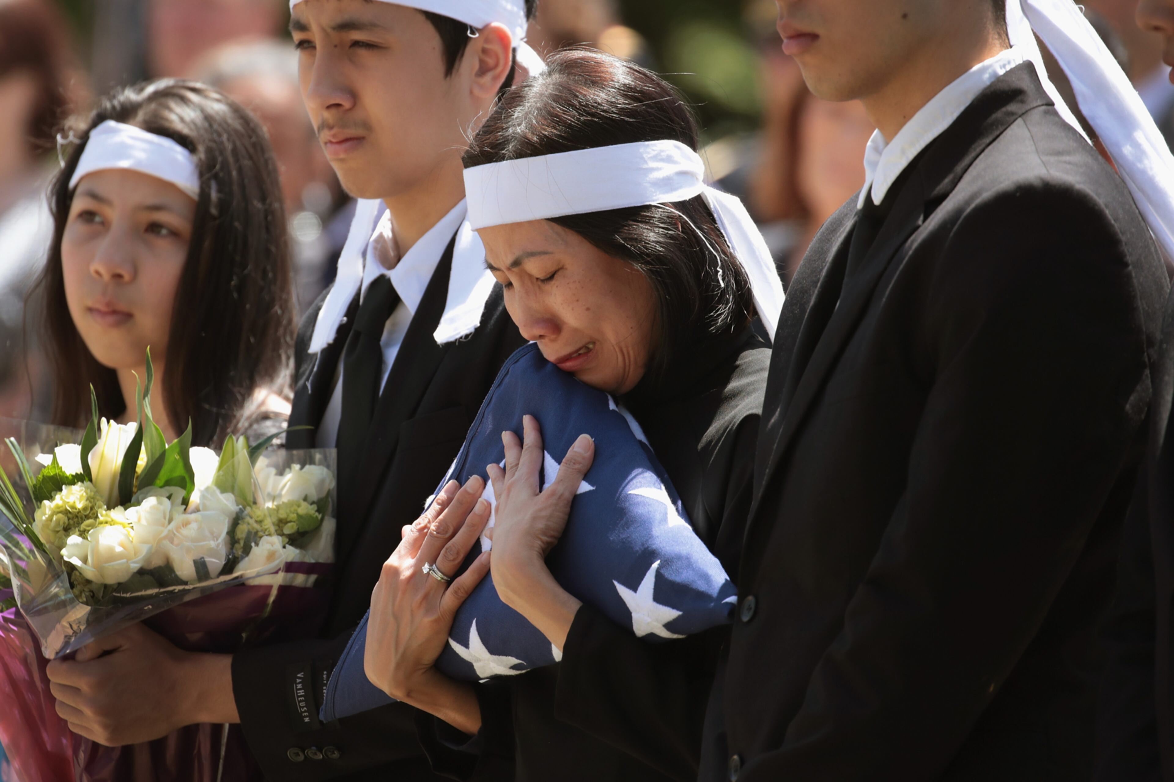 PORTLAND, OR - JUNE 05: Myhanh Best clutches the flag that draped the casket of her husband Ricky Best, an Army veteran and father of four, during a committal service at Willamette National Cemetery on June 5, 2017 in Portland, Oregon. Ricky Best, 53, and Taliesin Namkai-Meche, 23, were stabbed to death and Micah Fletcher,21, was severely injured after they tried to stop Jeremy Christian from harassing two teenage girls, one of whom was wearing a hijab, with racist taunts as they were riding a MAX commuter train. (Photo by Scott Olson/Getty Images)