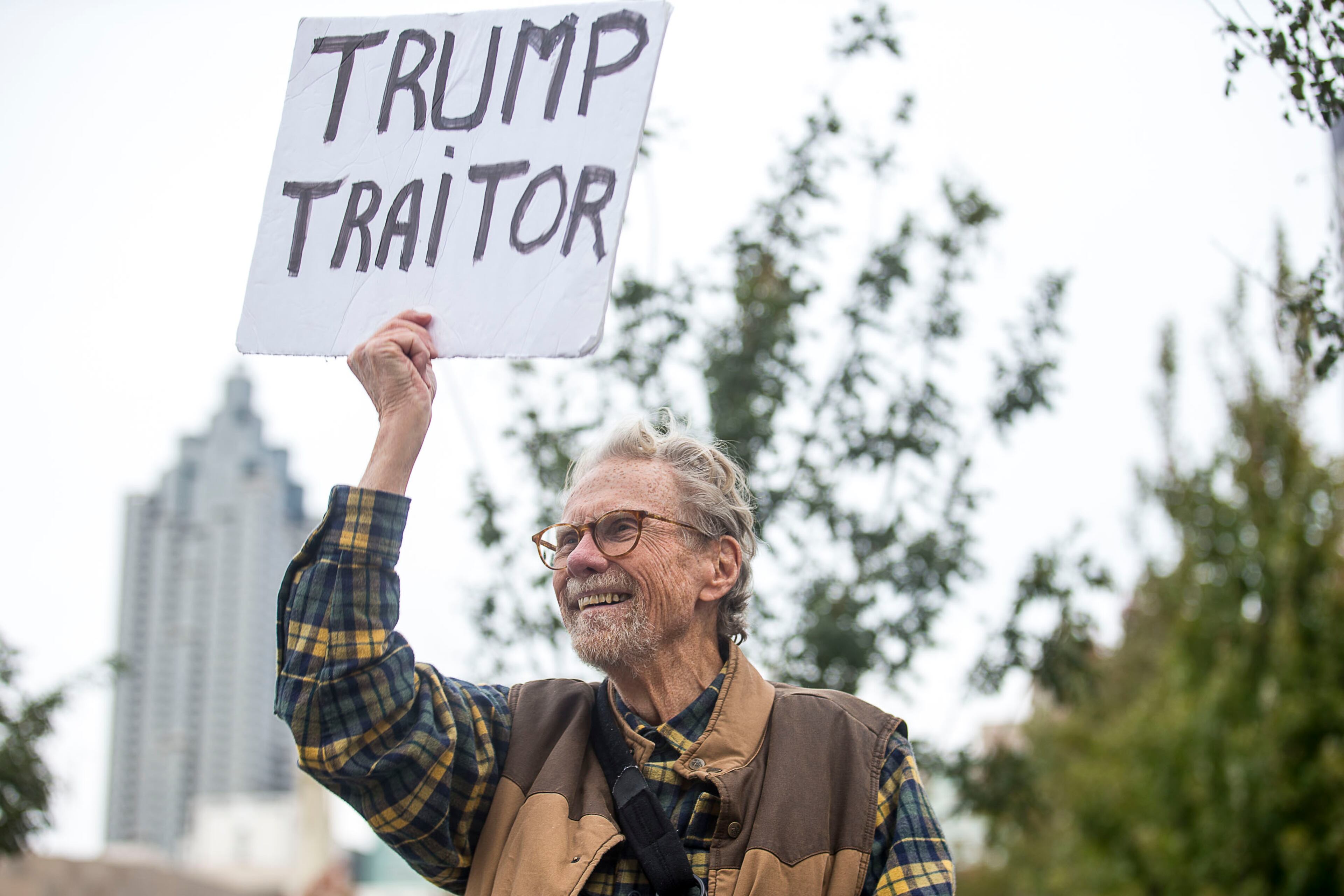 11/08/2019 -- Atlanta, Georgia -- Kevin Moran, 71, of Tucker, holds his protest sign during an anti-Trump rally at Centennial Olympic Park in downtown Atlanta, Friday, November 8, 2019. (Alyssa Pointer/Atlanta Journal Constitution)