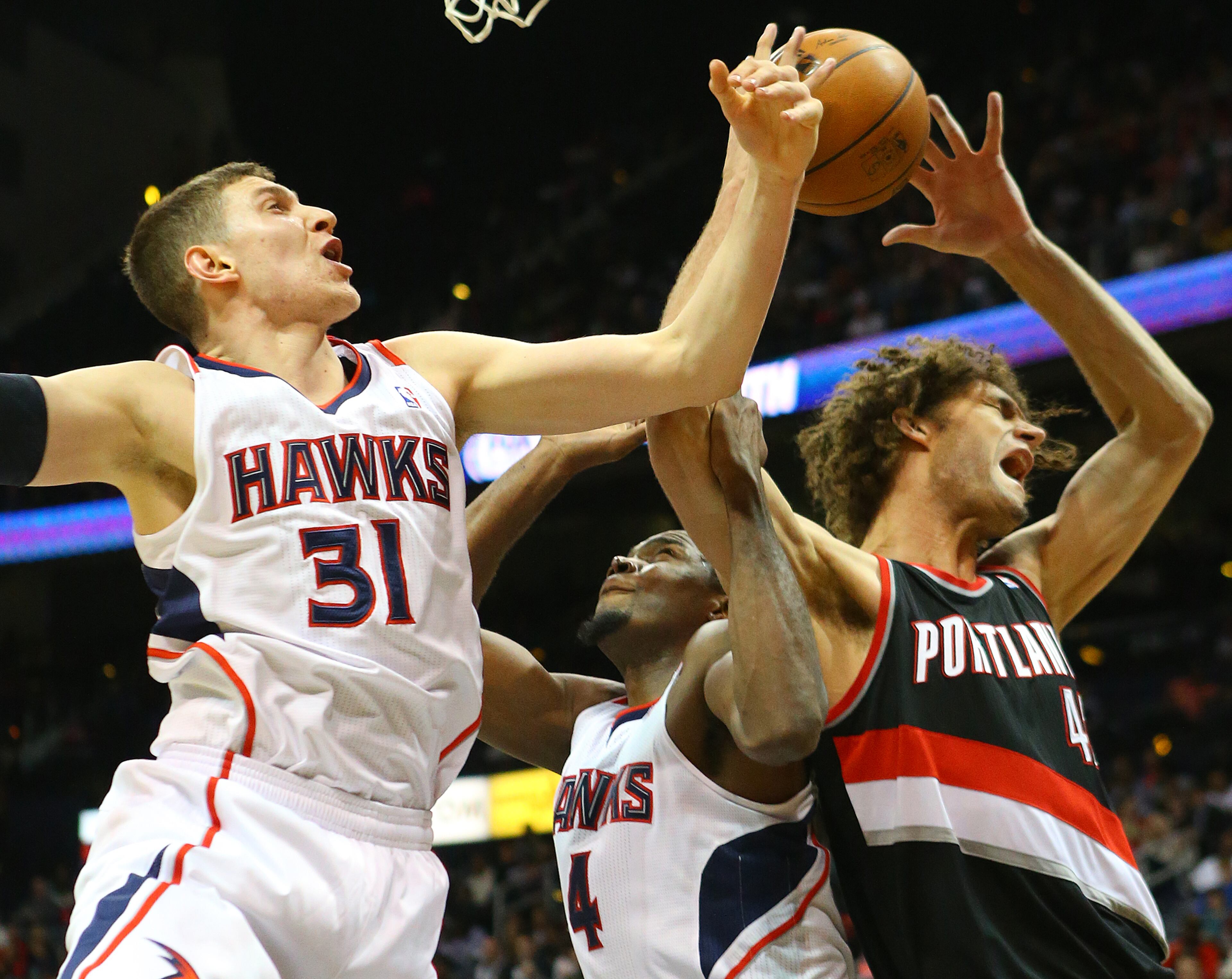 Hawks forwards Mike Muscala (left) and Paul Millsap double team Trail Blazers Robin Lopez under the basket blocking his shot during the second half of an NBA basketball game on Thursday, March 27, 2014, in Atlanta. The Trail Blazers won 100-85. CURTIS COMPTON / CCOMPTON@AJC.COM