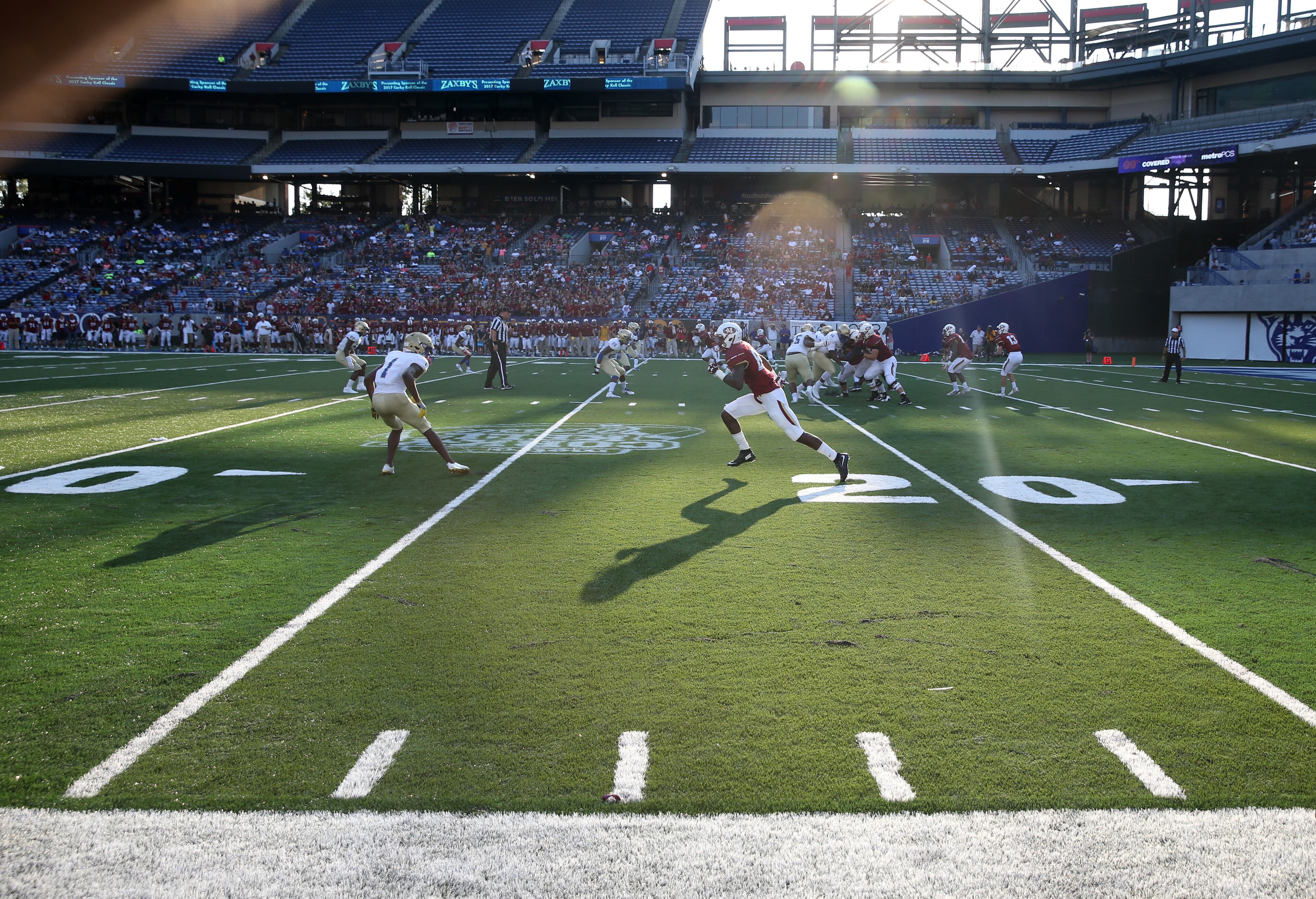 The sun streams across the field on an offensive play by Mill Creek in the first half against McEachern during the Corky Kell Classic at Georgia State Stadium Saturday evening.
