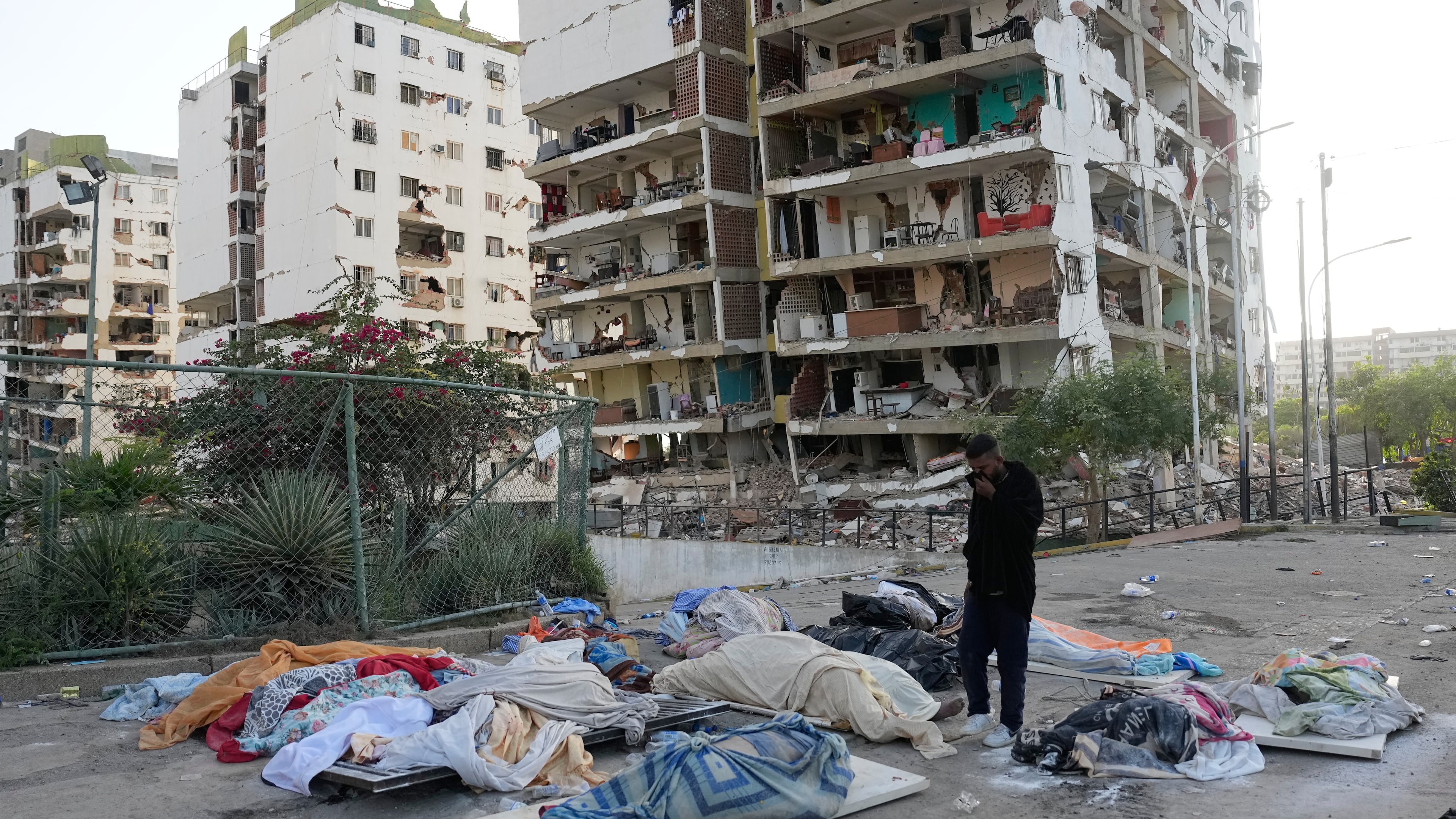 Ezequiel Frontado looks at covered bodies while searching for missing relatives three days after earthquakes struck Catia La Mar, Venezuela, Saturday, June 27, 2026. (AP Photo/Fernando Vergara)