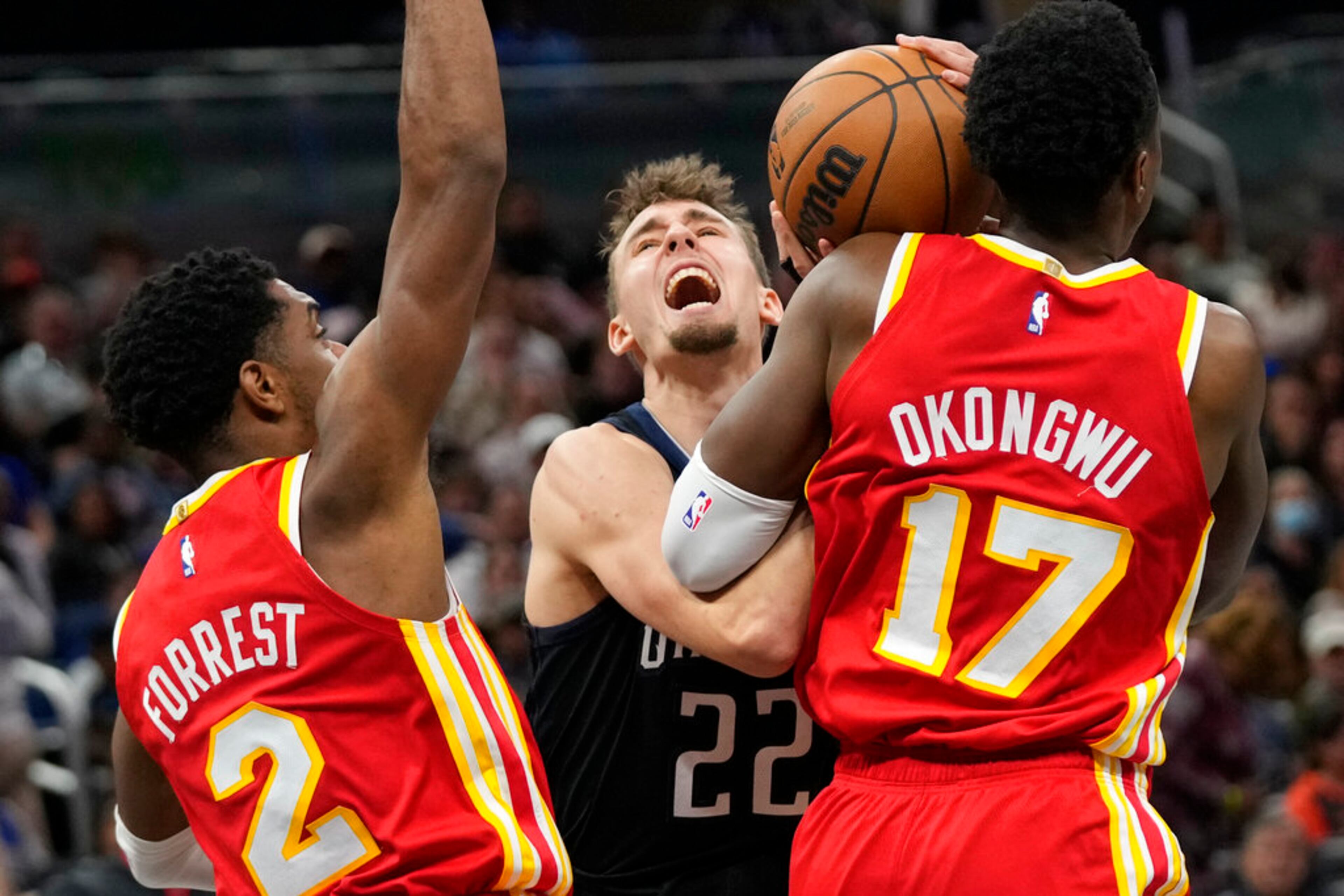Orlando Magic's Franz Wagner (22) tries to get off a shot as he is defended by Atlanta Hawks' Trent Forrest (2) and Onyeka Okongwu (17) during the second half of an NBA basketball game, Wednesday, Dec. 14, 2022, in Orlando, Fla. (AP Photo/John Raoux)
