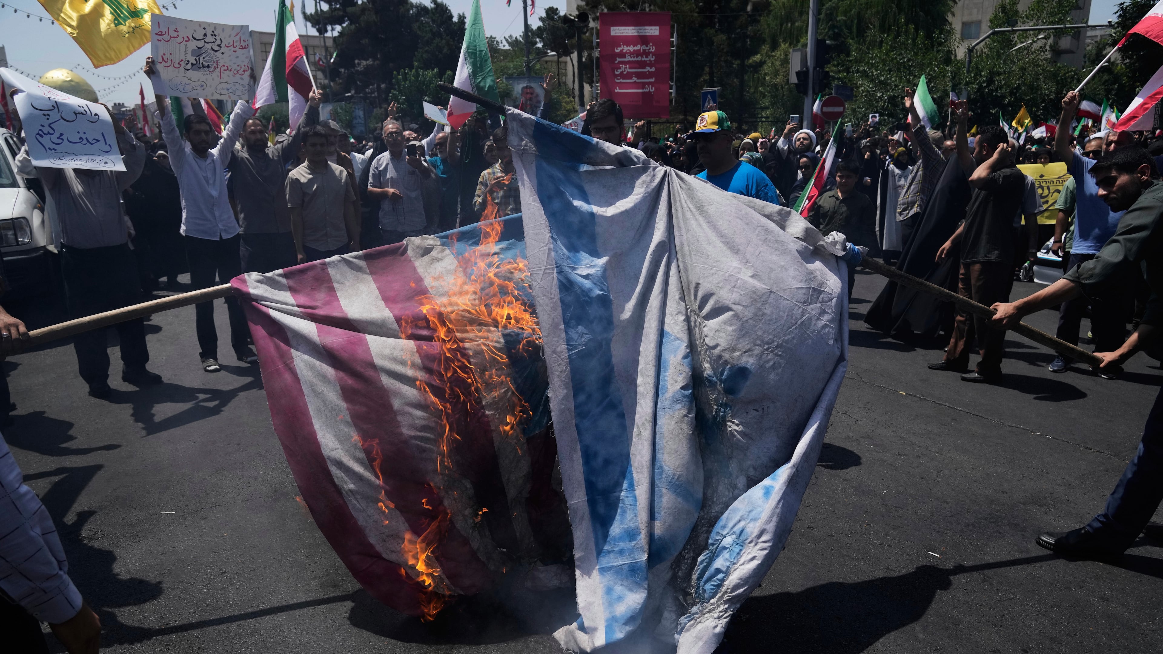 FILE - Iranian protestors burn representations of the Israeli and U.S. flags during a protest to condemn Israeli attacks on multiple cities across Iran, after the Friday prayers ceremony in Tehran, Iran, Friday, June 20, 2025. (AP Photo/Vahid Salemi), File)