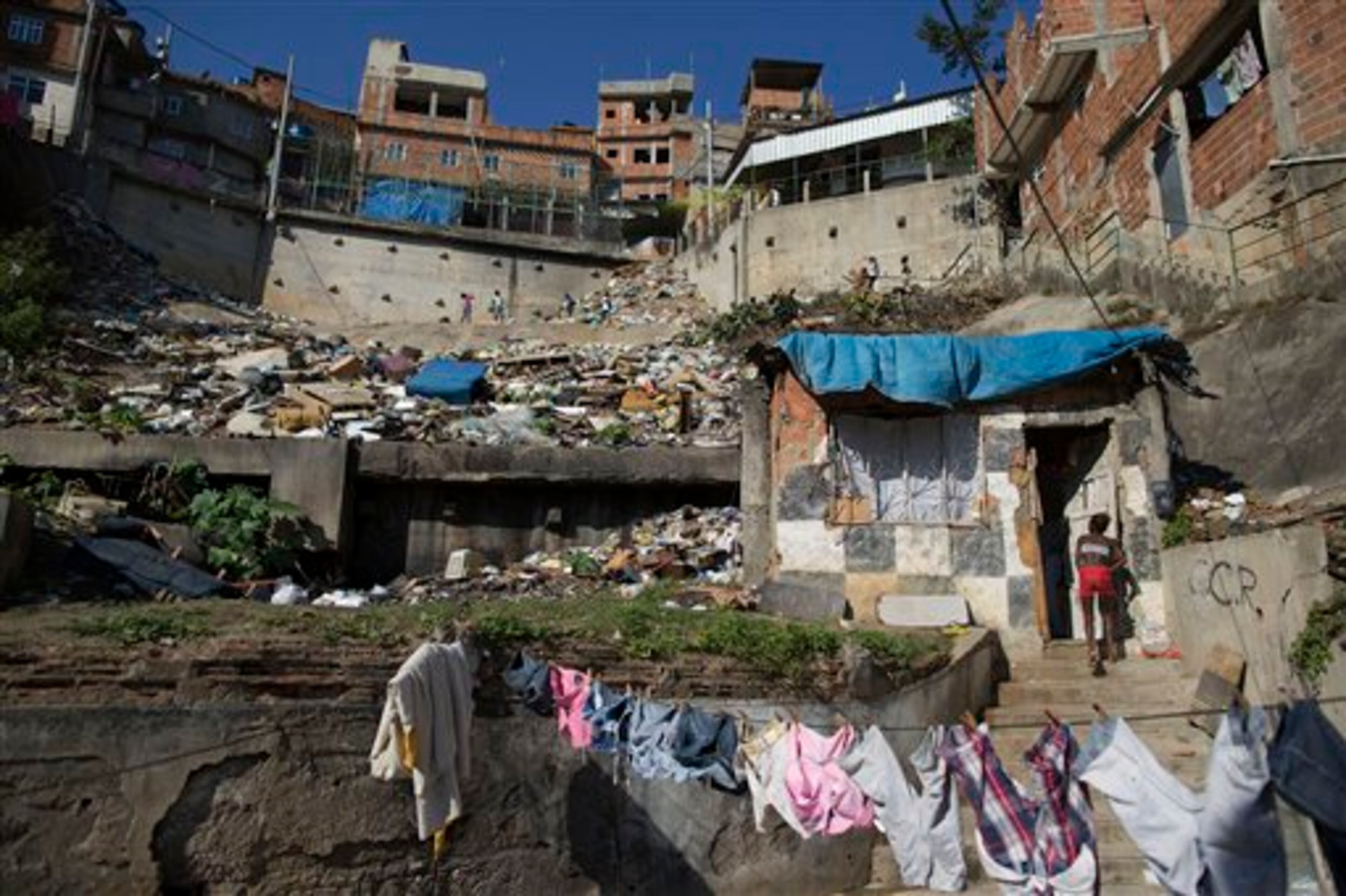 In this Monday, June 2, 2014, a woman enters her shack on a hillside next to a landfill in the Mangueira slum in Rio de Janeiro, Brazil. Less than half a kilometer separates the sprawling slum from the Maracana stadium, where seven World Cup matches will be played, including the July 13 final. (AP Photo/Leo Correa)