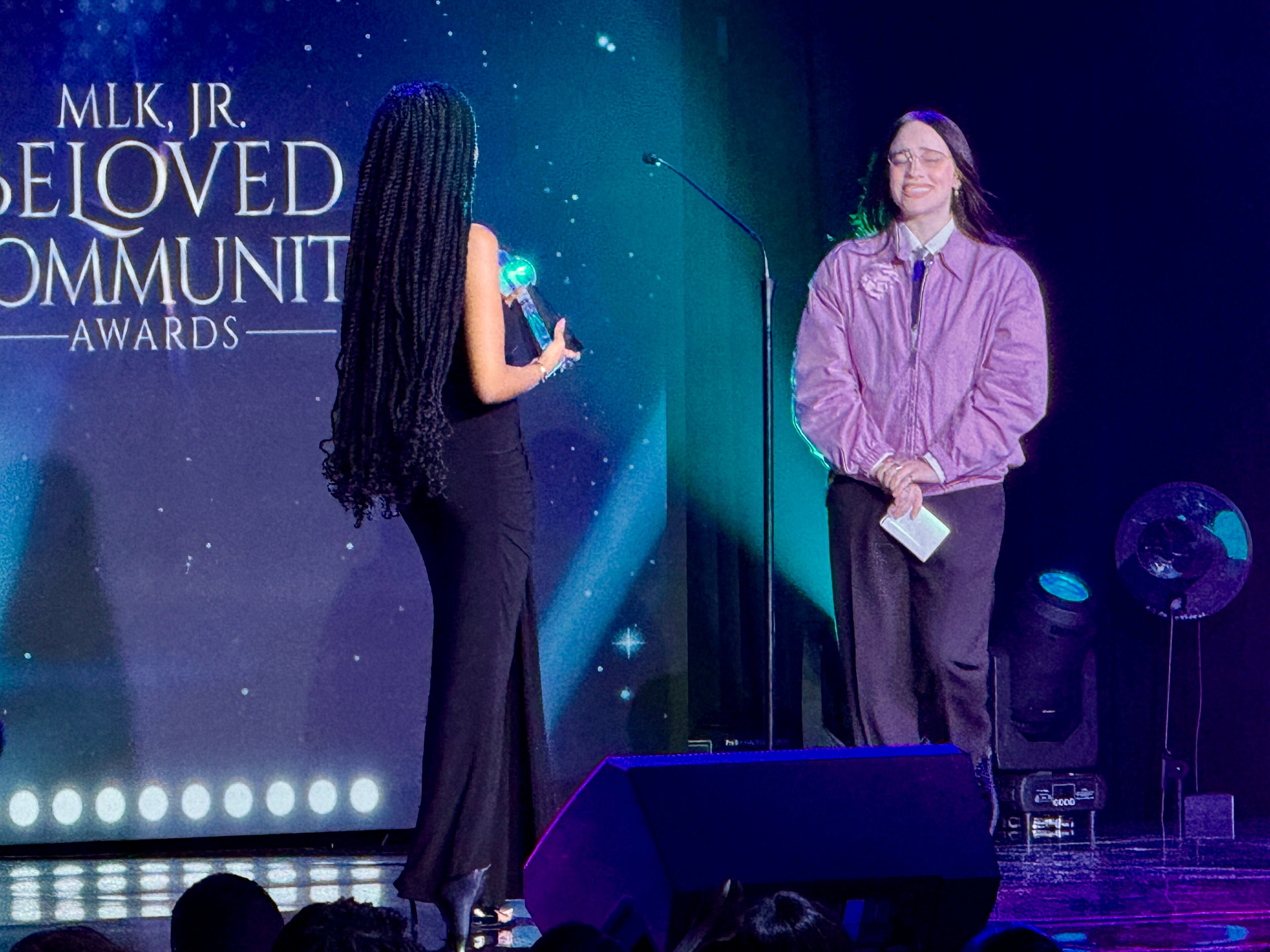 Musician Billie Eilish (right) is presented with the Environmental Justice Award at the MLK Jr. Beloved Community Awards in Atlanta for her sustainable tour practices, fashion activism and $11.5 million donation to support climate justice and food equity organizations. (Danielle Charbonneau/AJC)