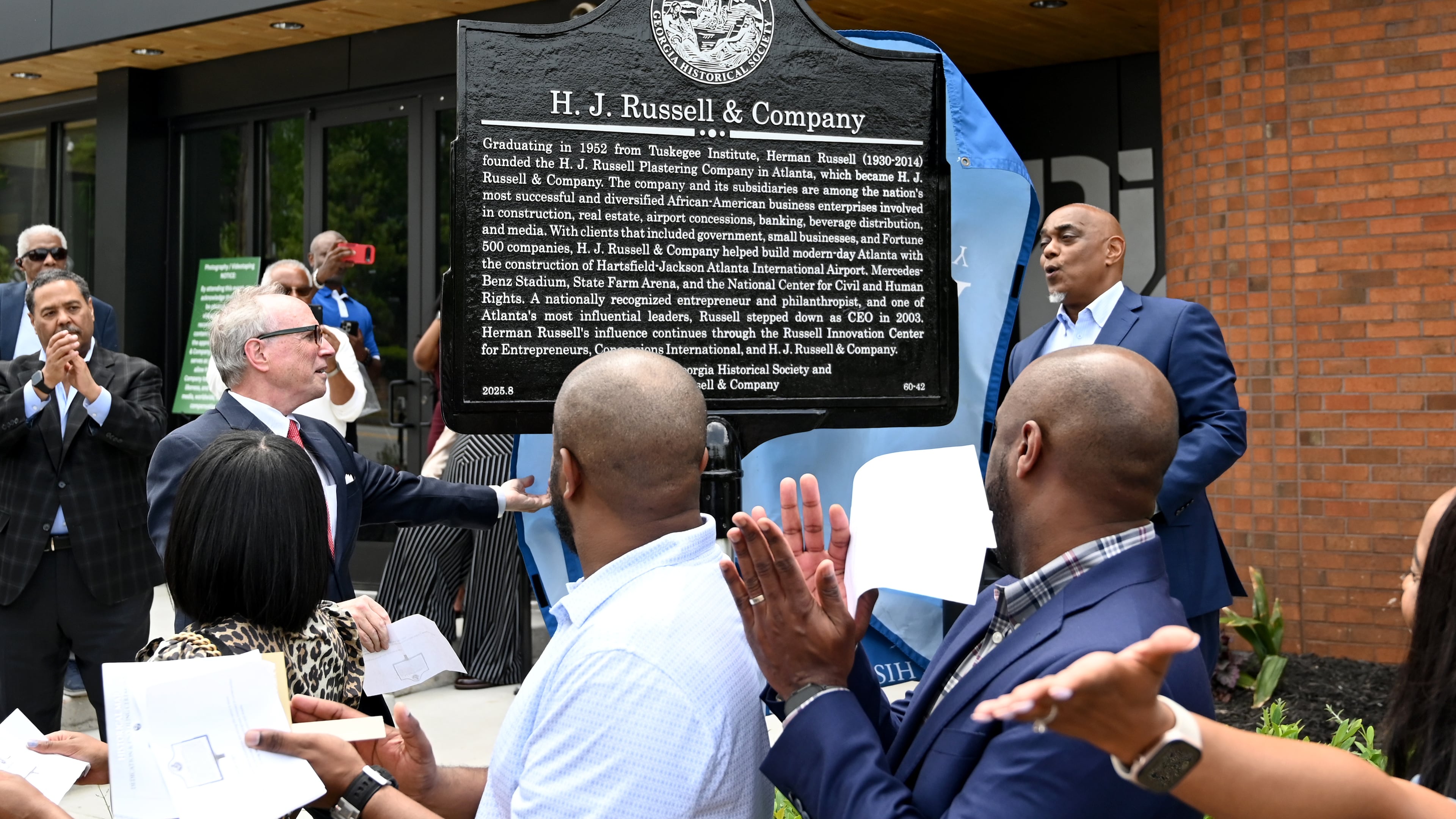 W. Todd Groce (left), president and CEO of the Georgia Historical Society, and Michael B. Russell Sr., CEO of H.J. Russell & Co, unveil a marker commemorating the company’s original headquarters April 29, 2026. (Hyosub Shin/AJC)