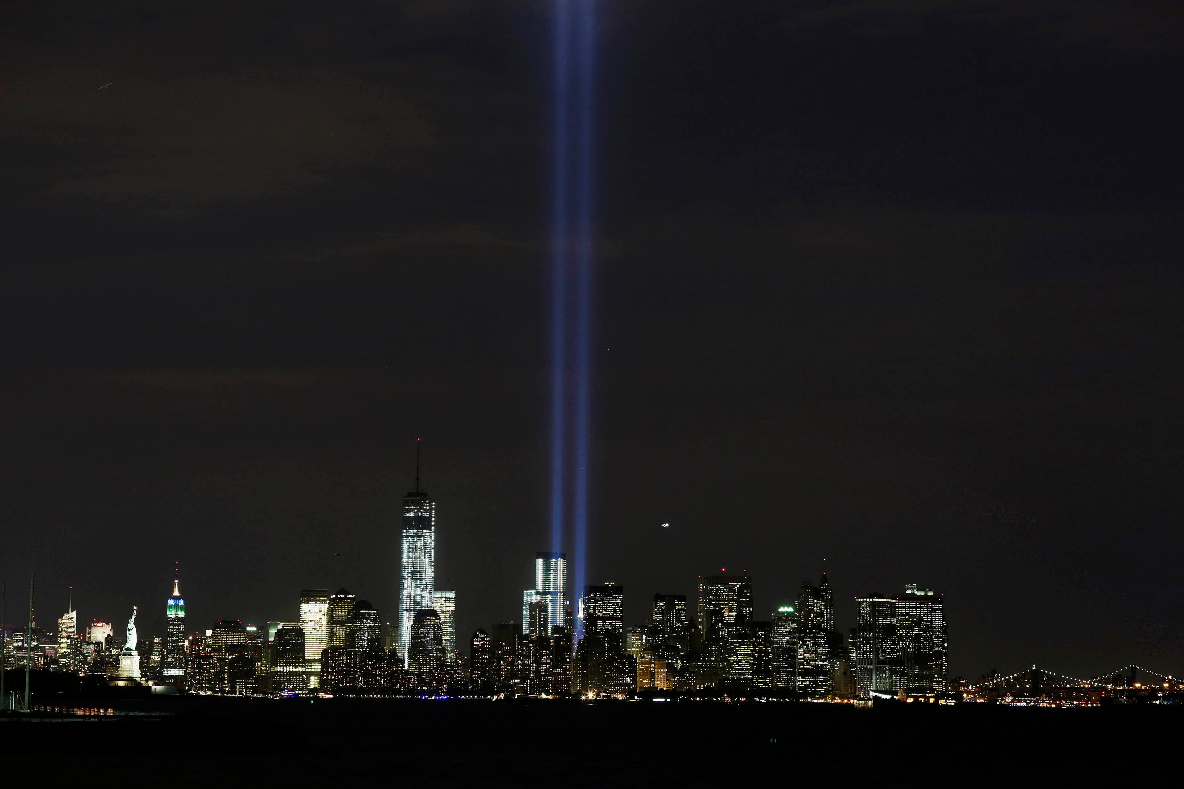 The Tribute in Light rises above the lower Manhattan skyline and One World Trade Center, center left, in a test of the memorial light display, Monday, Sept. 9, 2013 in New York. The twin beams of light will also appear Wednesday, Sept. 11, twelve years after the terrorist attacks of Sept. 11, 2011. The Statue of Liberty and Empire State Building are far left. The Brooklyn Bridge is far right. (AP Photo/Mark Lennihan)