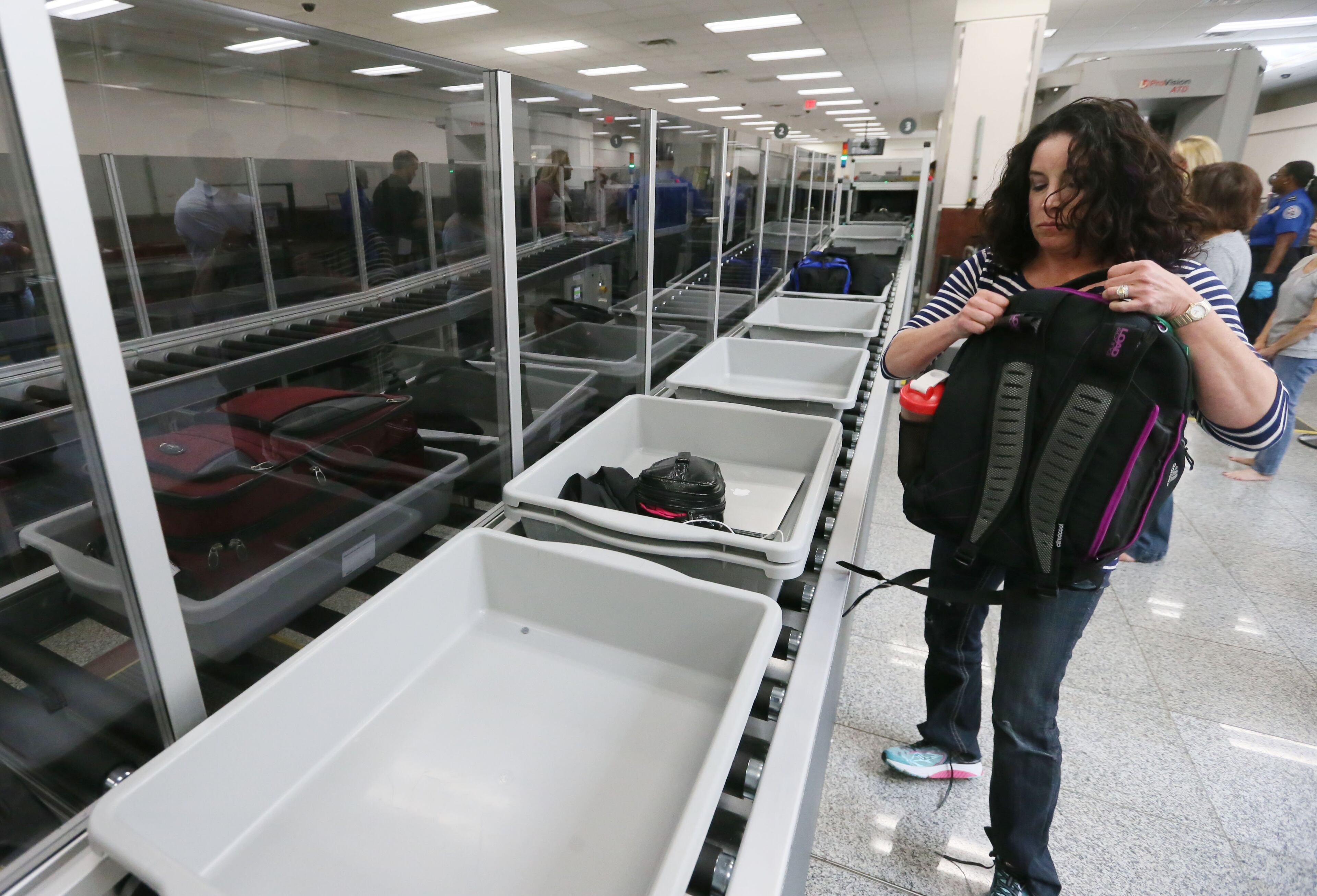 Ami Ewald, from Ohio, , picks up bags after going through the new process. She said she didn't think it was an improvement. TSA unveiled new security "smart lanes" that have been installed in the South Security Checkpoint, which feature automated equipment that handles baggage. BOB ANDRES / BANDRES@AJC.COM